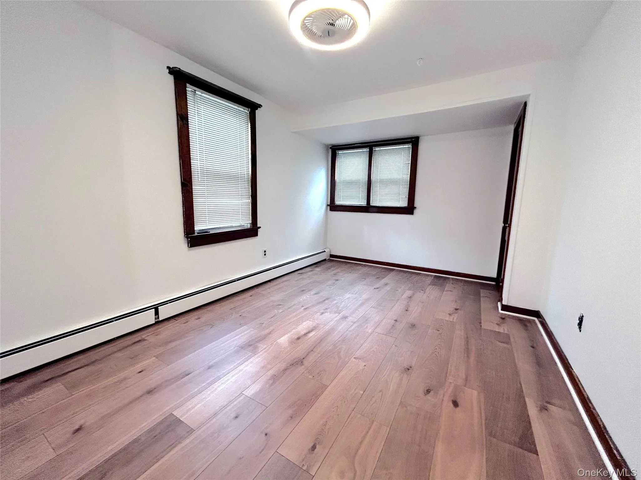 Empty room with baseboard heating and light wood-style floors Empty room with baseboard heating and light wood-style floors