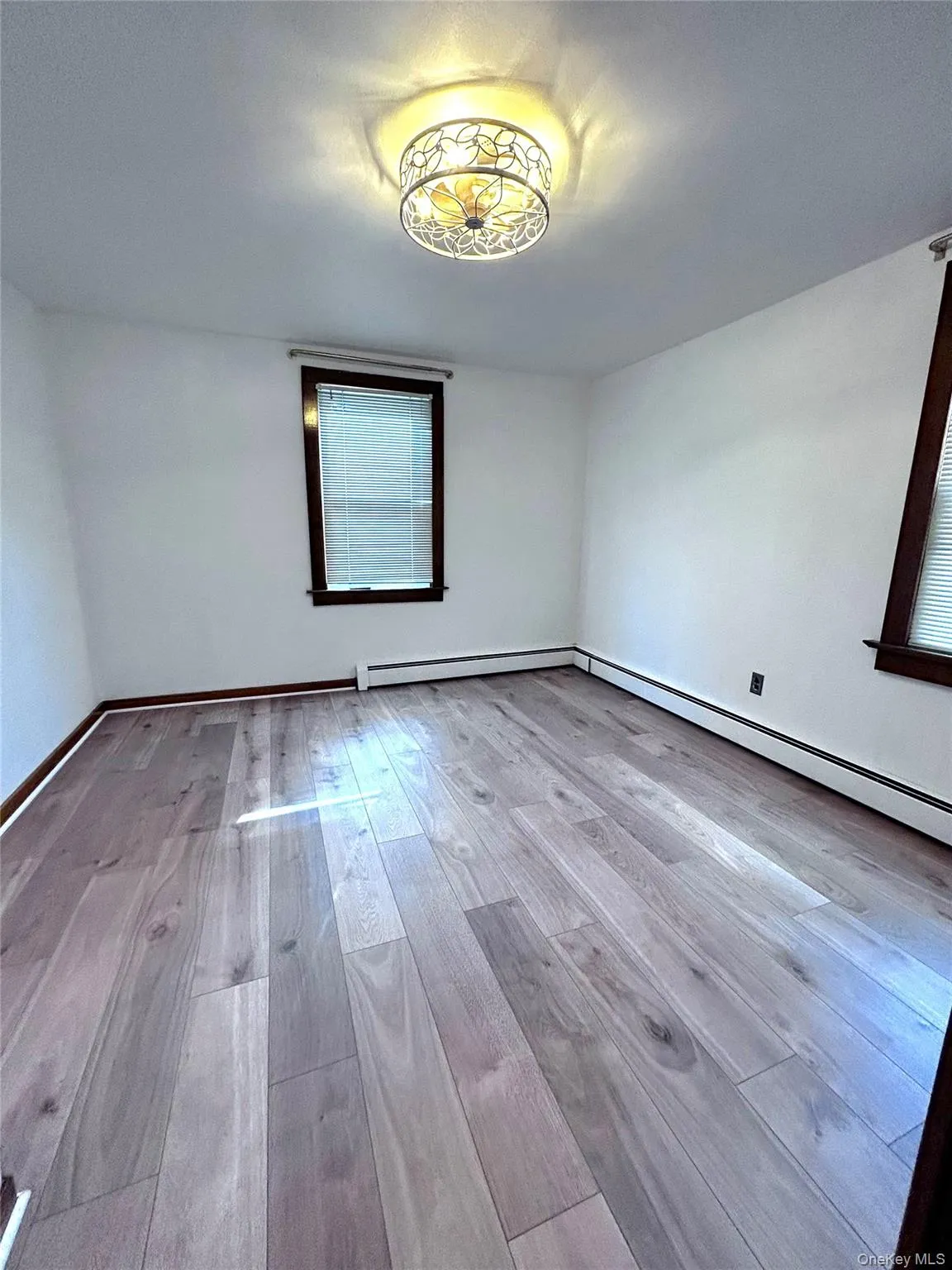 Unfurnished room with light wood finished floors and baseboards Unfurnished room with light wood finished floors and baseboards