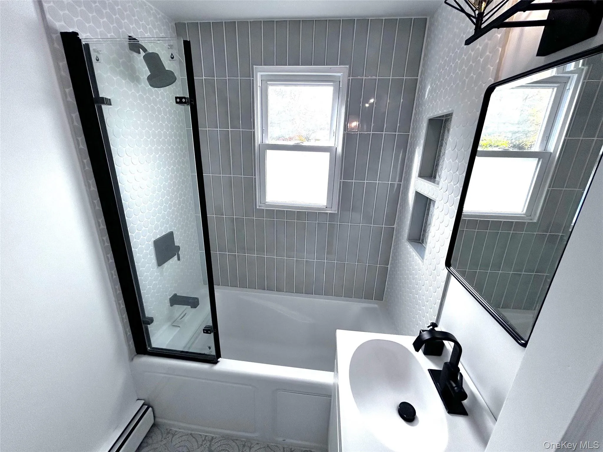 Bathroom featuring tub / shower combination, a baseboard radiator, and vanity Bathroom featuring tub / shower combination, a baseboard radiator, and vanity