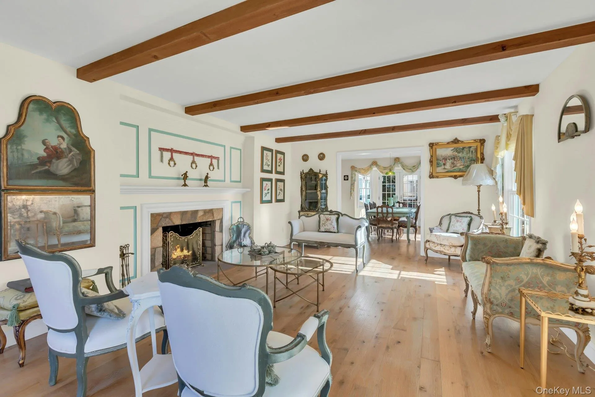 Staged Living area featuring a stone fireplace, light wood-style floors, and beamed ceiling Staged Living area featuring a stone fireplace, light wood-style floors, and beamed ceiling