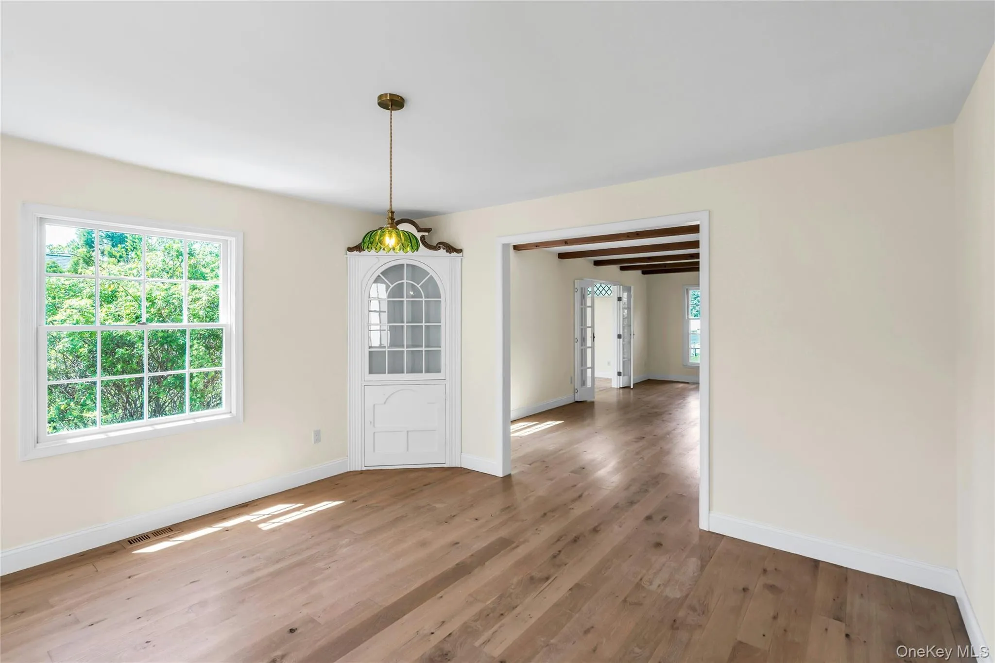 Hardwood flooring extends throughout this room, featuring a built-in corner cabinet with glass paned doors Hardwood flooring extends throughout this room, featuring a built-in corner cabinet with glass paned doors