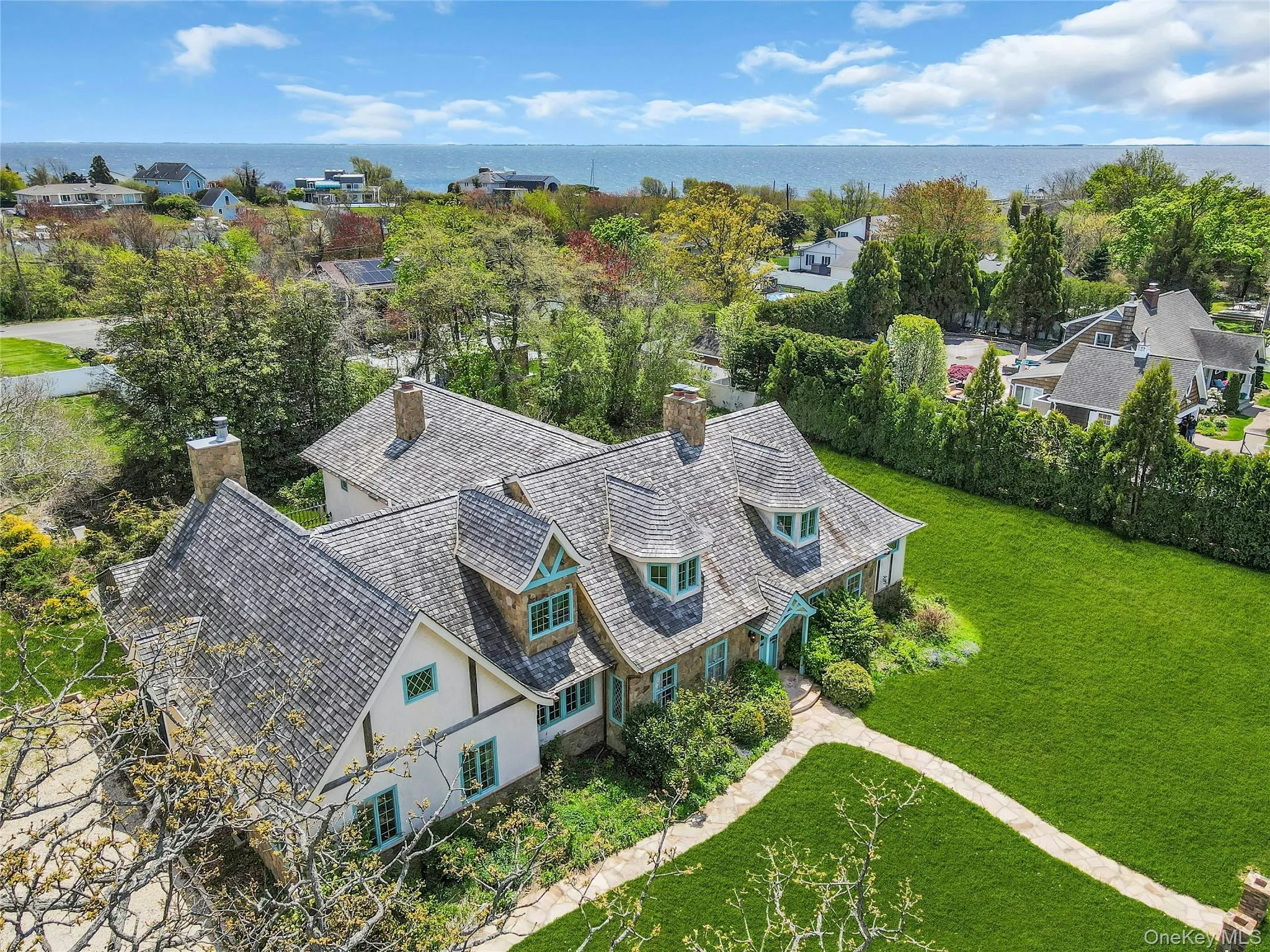 Stone and stucco residence featuring multiple dormers, a cedar shake roof, and a stone walkway Stone and stucco residence featuring multiple dormers, a cedar shake roof, and a stone walkway