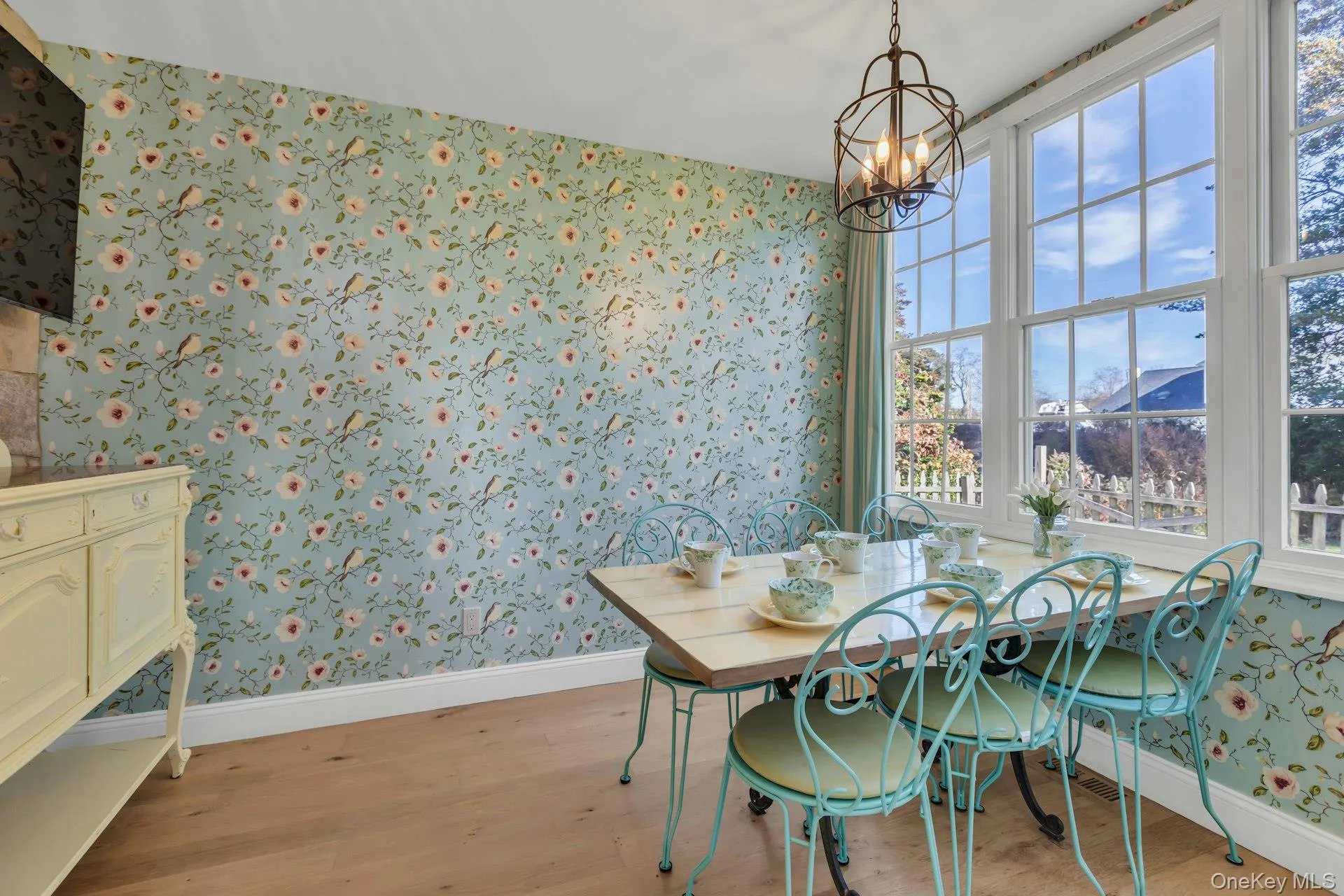 Dining space with wallpapered walls, light wood-style flooring, and a chandelier Dining space with wallpapered walls, light wood-style flooring, and a chandelier