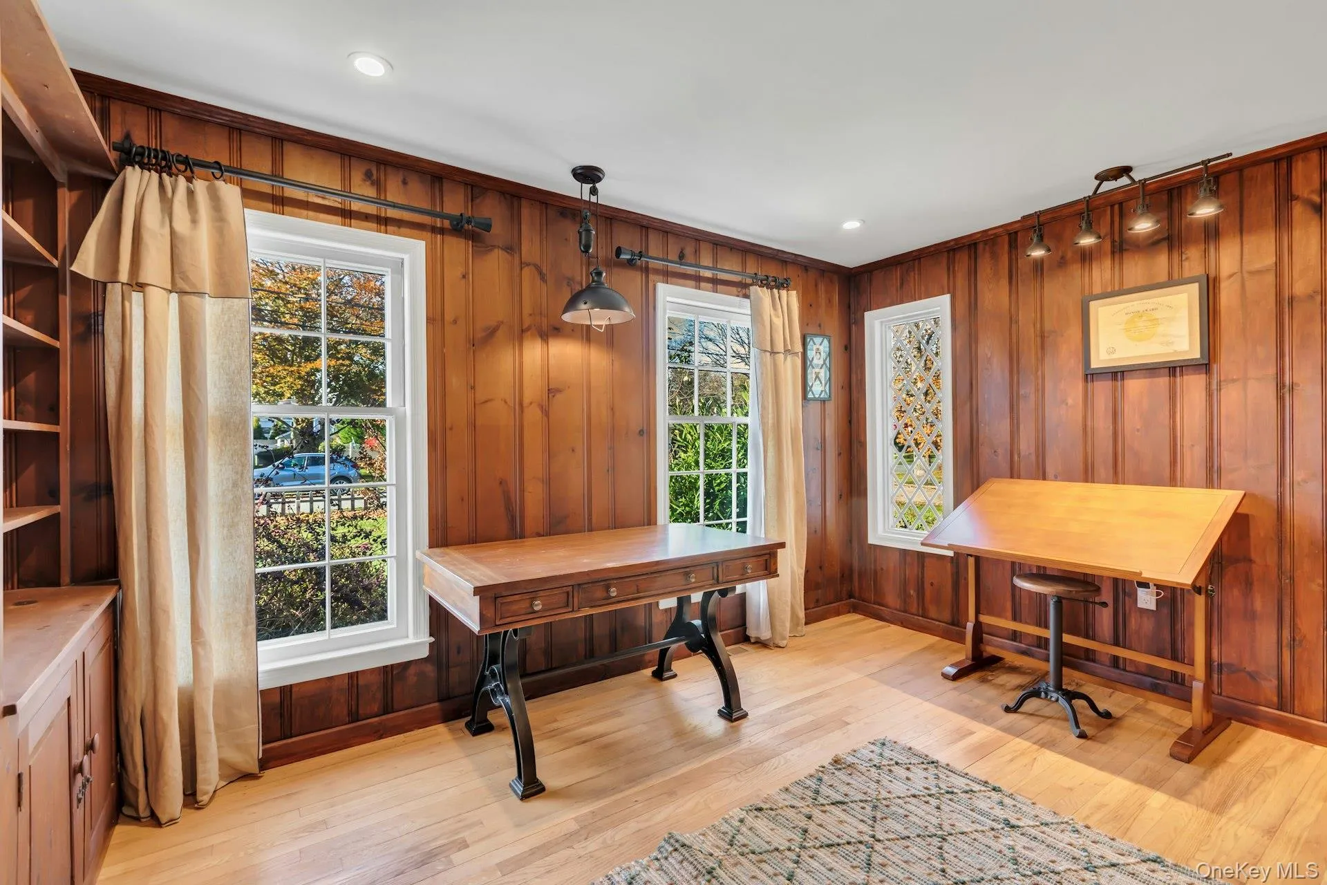 Home office featuring light wood-style flooring, wood walls, and recessed lighting Home office featuring light wood-style flooring, wood walls, and recessed lighting