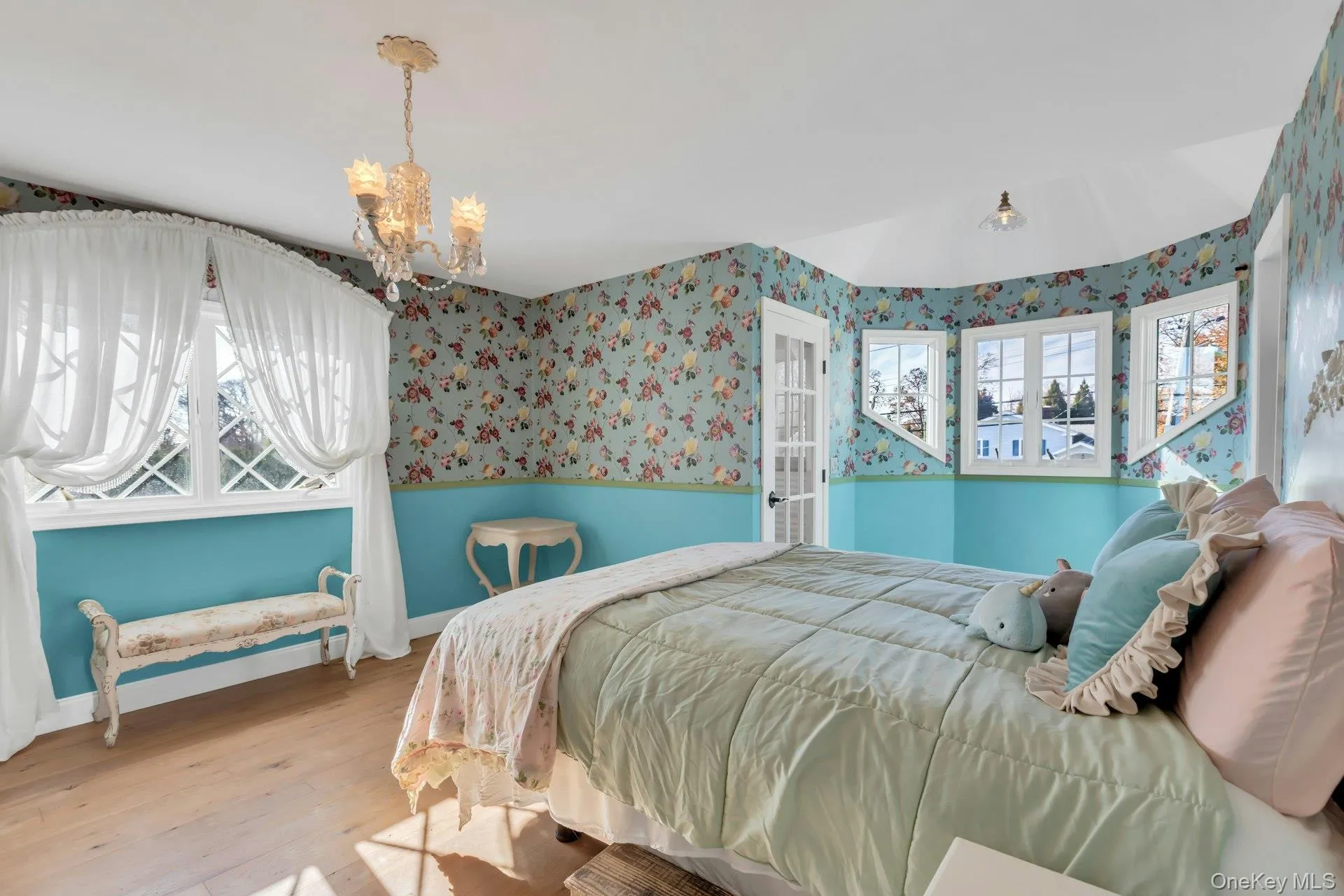 Staged Bedroom featuring wallpapered walls, hardwood / wood-style floors, and a chandelier 2 walk in closets Staged Bedroom featuring wallpapered walls, hardwood / wood-style floors, and a chandelier 2 walk in closets