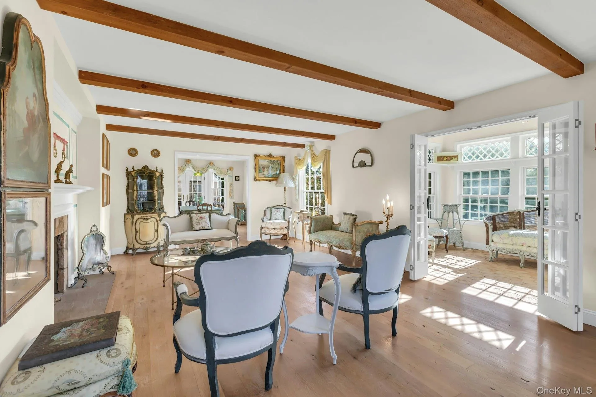 Staged Living room with a high end fireplace, french doors, beam ceiling, and light wood finished floors Staged Living room with a high end fireplace, french doors, beam ceiling, and light wood finished floors