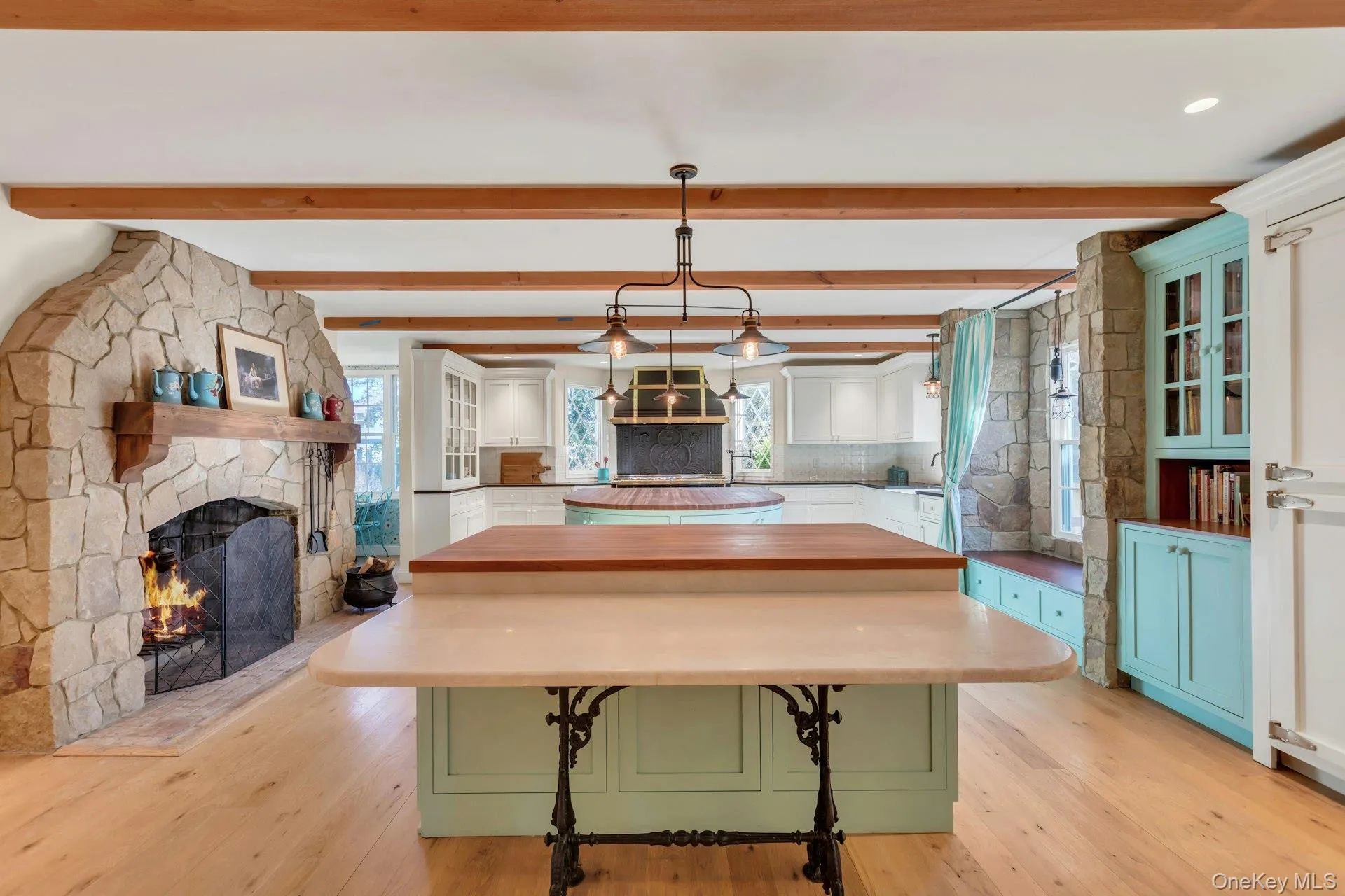 Kitchen with white and teal cabinetry, a fireplace, glass insert cabinets, and beamed ceiling Kitchen with white and teal cabinetry, a fireplace, glass insert cabinets, and beamed ceiling