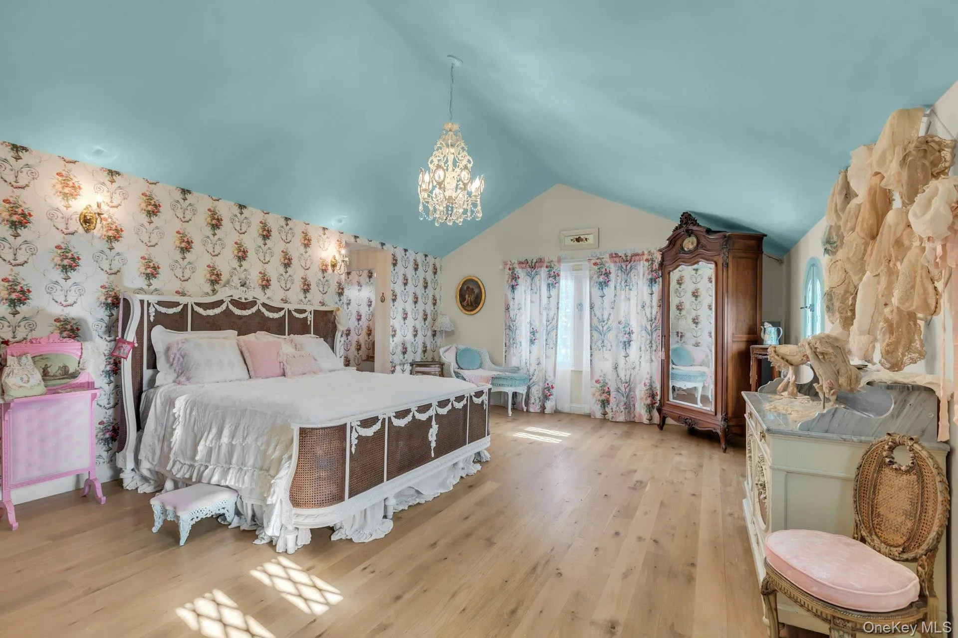 Bedroom featuring wallpapered walls, lofted ceiling, a chandelier, and wood finished floors Bedroom featuring wallpapered walls, lofted ceiling, a chandelier, and wood finished floors