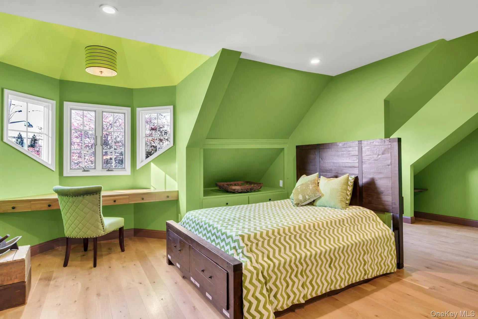 Bedroom featuring light wood finished floors, vaulted ceiling, built in desk and walk in closet Bedroom featuring light wood finished floors, vaulted ceiling, built in desk and walk in closet
