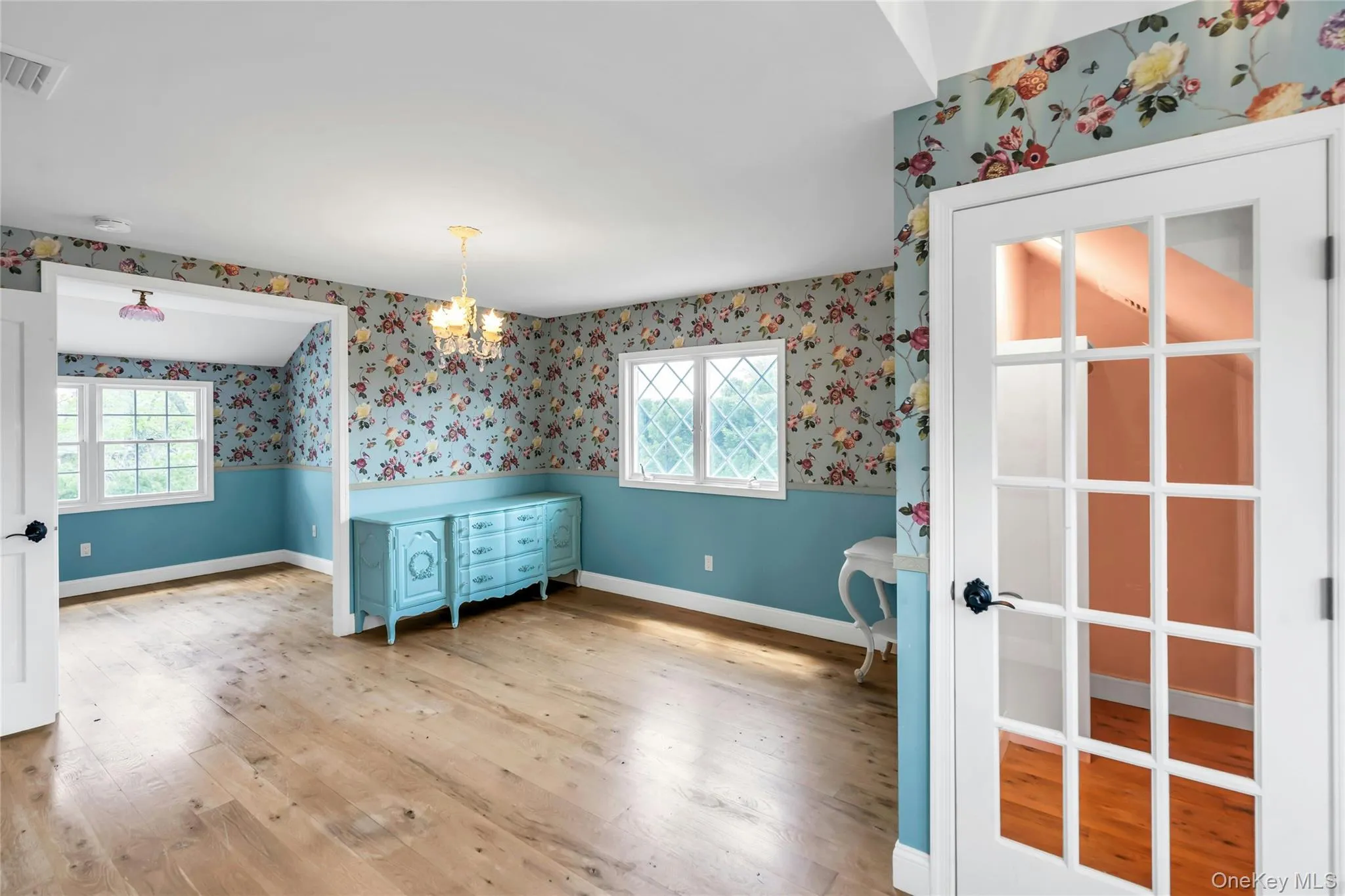 Hardwood flooring throughout featuring floral patterned wallpaper Hardwood flooring throughout featuring floral patterned wallpaper