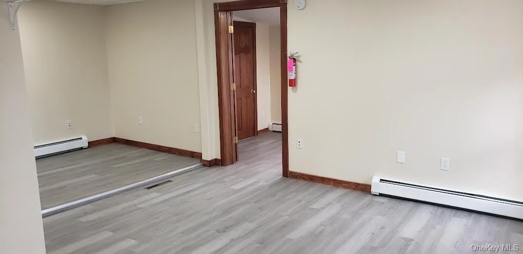 Unfurnished room featuring light wood-type flooring and a baseboard radiator Unfurnished room featuring light wood-type flooring and a baseboard radiator