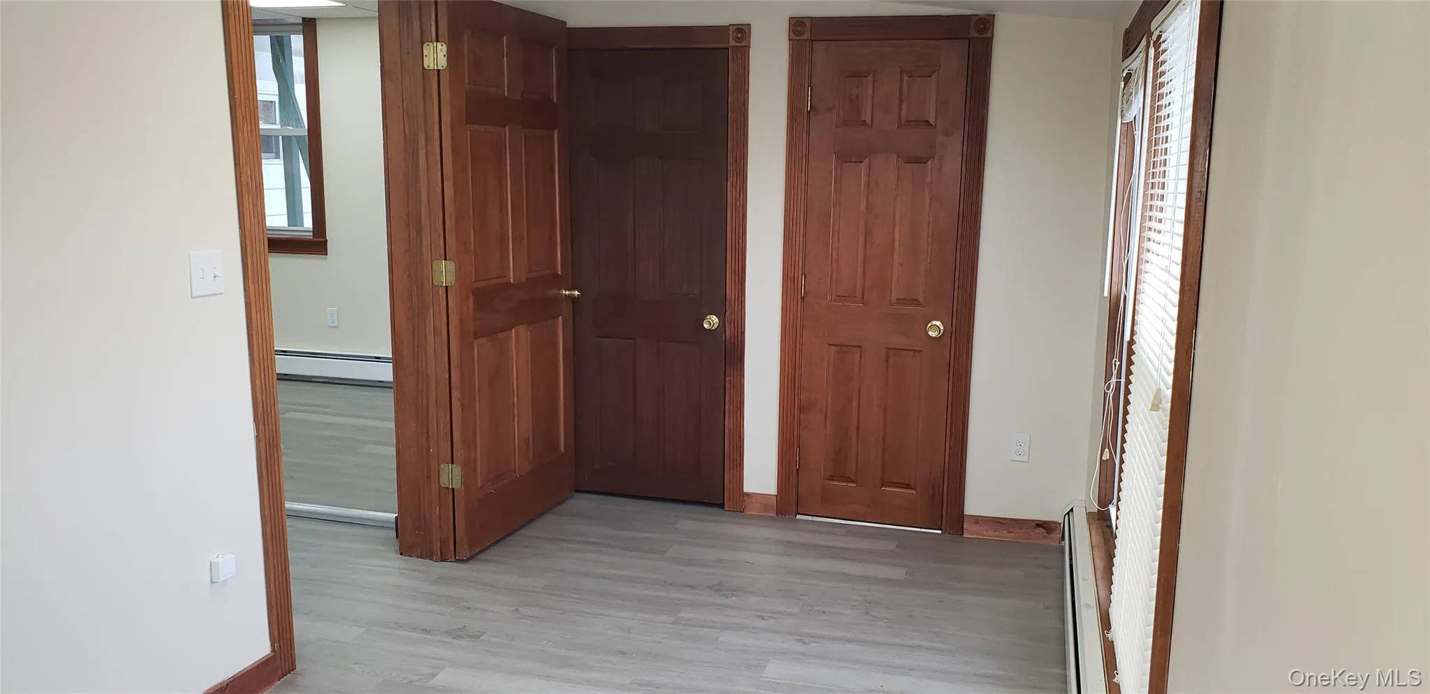 Corridor with light wood-style floors, healthy amount of natural light, and a baseboard heating unit Corridor with light wood-style floors, healthy amount of natural light, and a baseboard heating unit