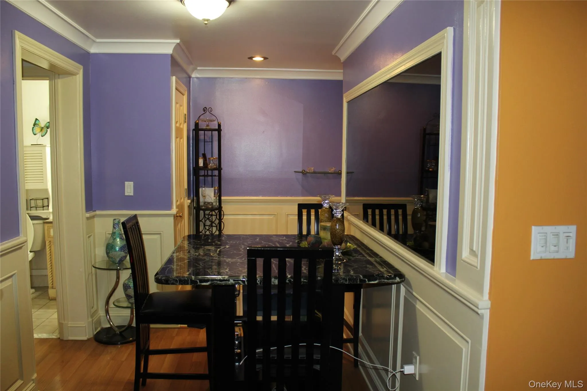 Dining space with a wainscoted wall, a decorative wall, ornamental molding, and dark wood-style floors Dining space with a wainscoted wall, a decorative wall, ornamental molding, and dark wood-style floors