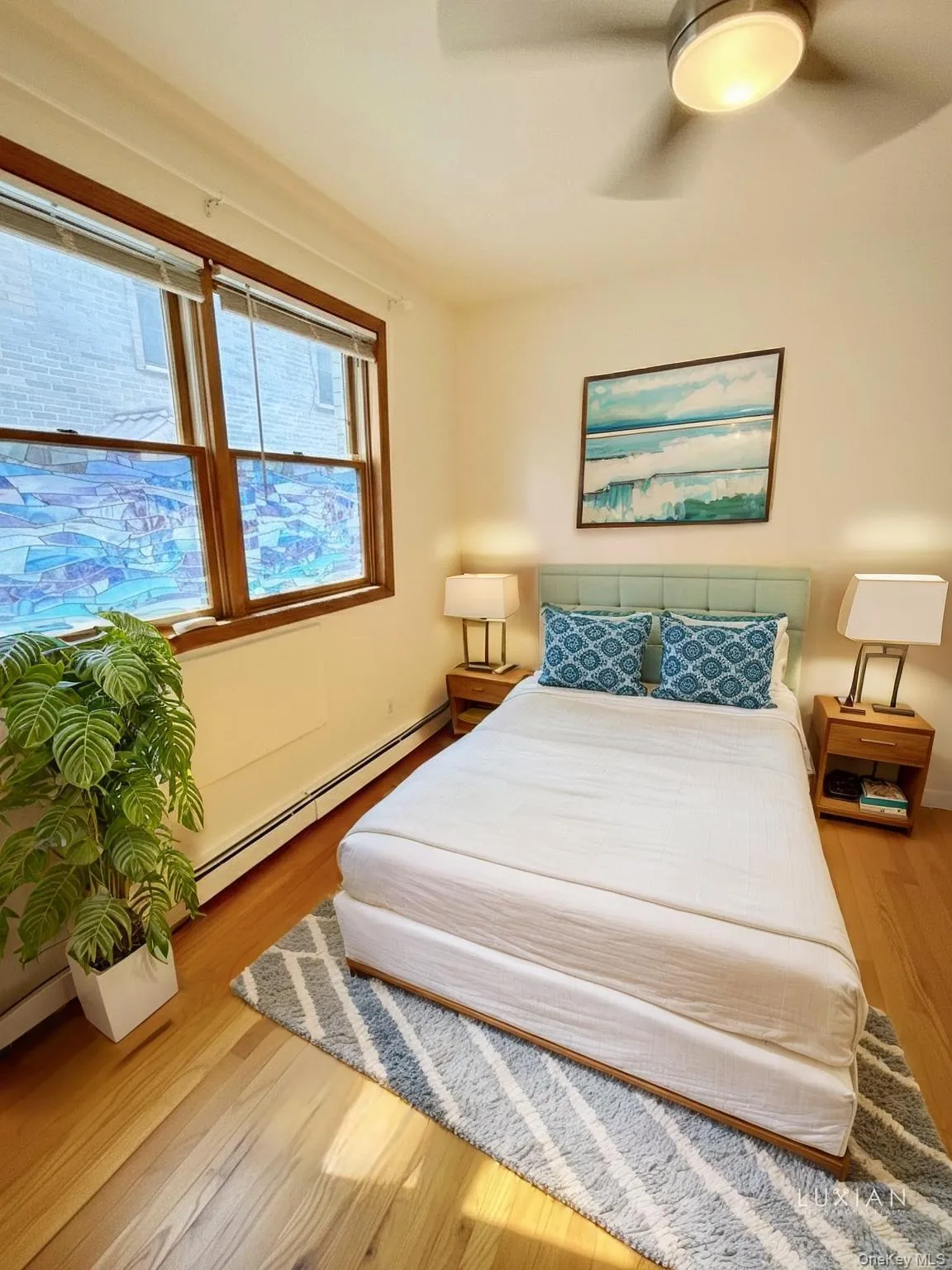 Bedroom with baseboard heating, a ceiling fan, and light wood-style flooring Bedroom with baseboard heating, a ceiling fan, and light wood-style flooring