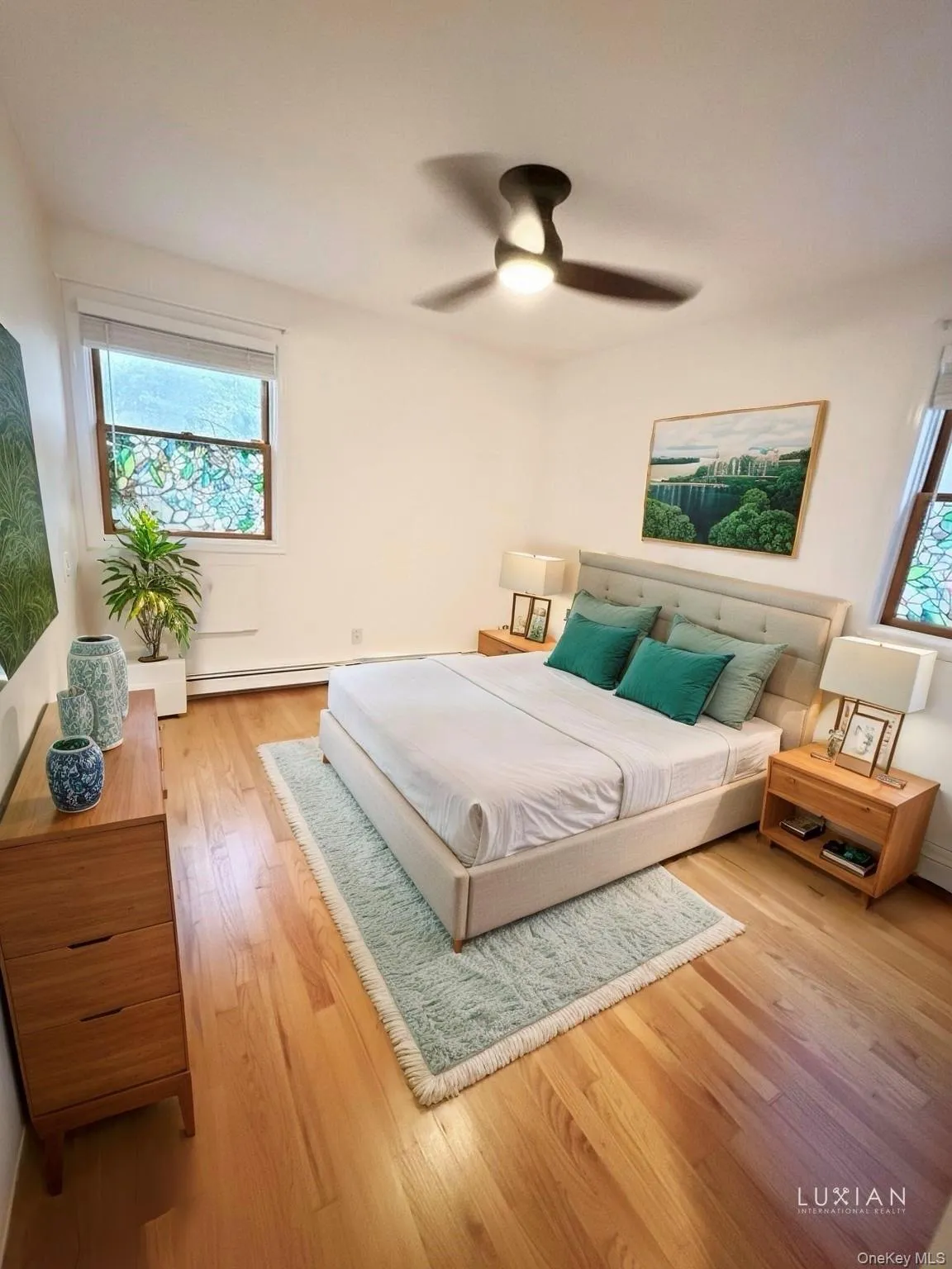 Bedroom with light wood finished floors, ceiling fan, and a baseboard heating unit Bedroom with light wood finished floors, ceiling fan, and a baseboard heating unit