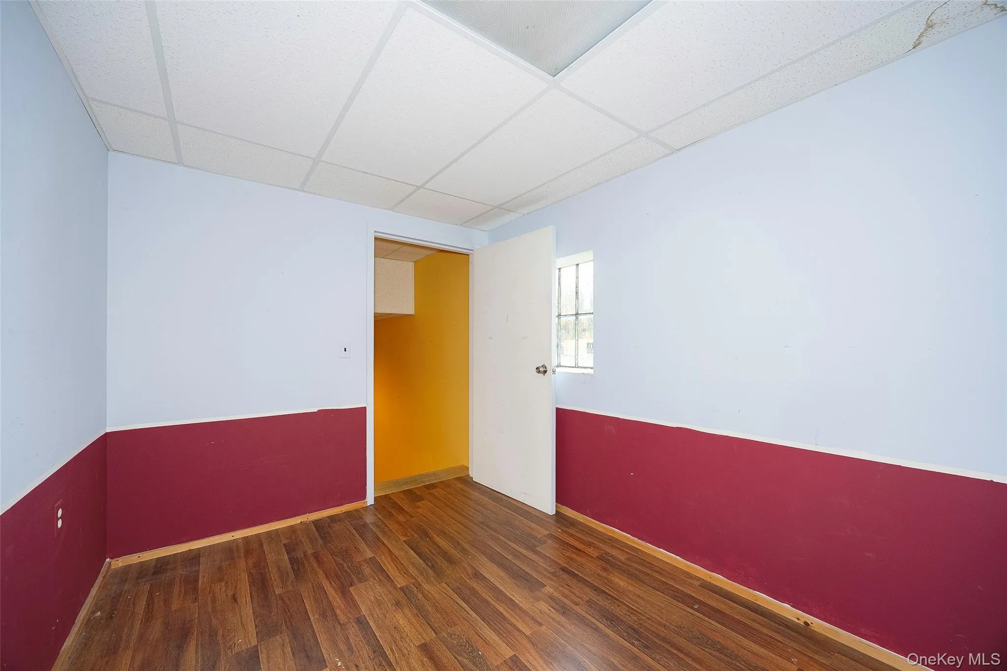 Unfurnished room with a paneled ceiling and dark wood-style floors Unfurnished room with a paneled ceiling and dark wood-style floors