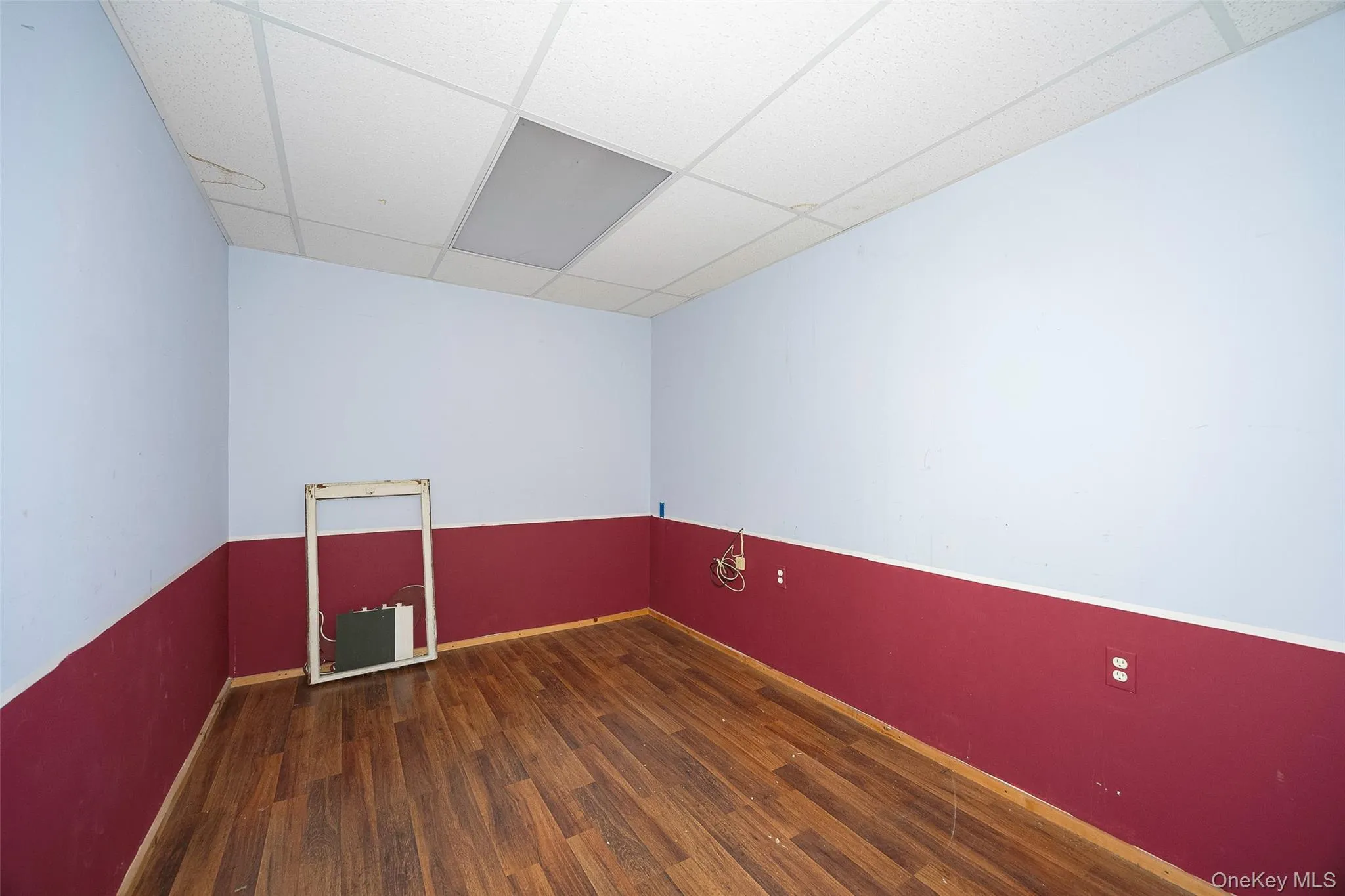 Empty room featuring a paneled ceiling and dark wood-style flooring Empty room featuring a paneled ceiling and dark wood-style flooring