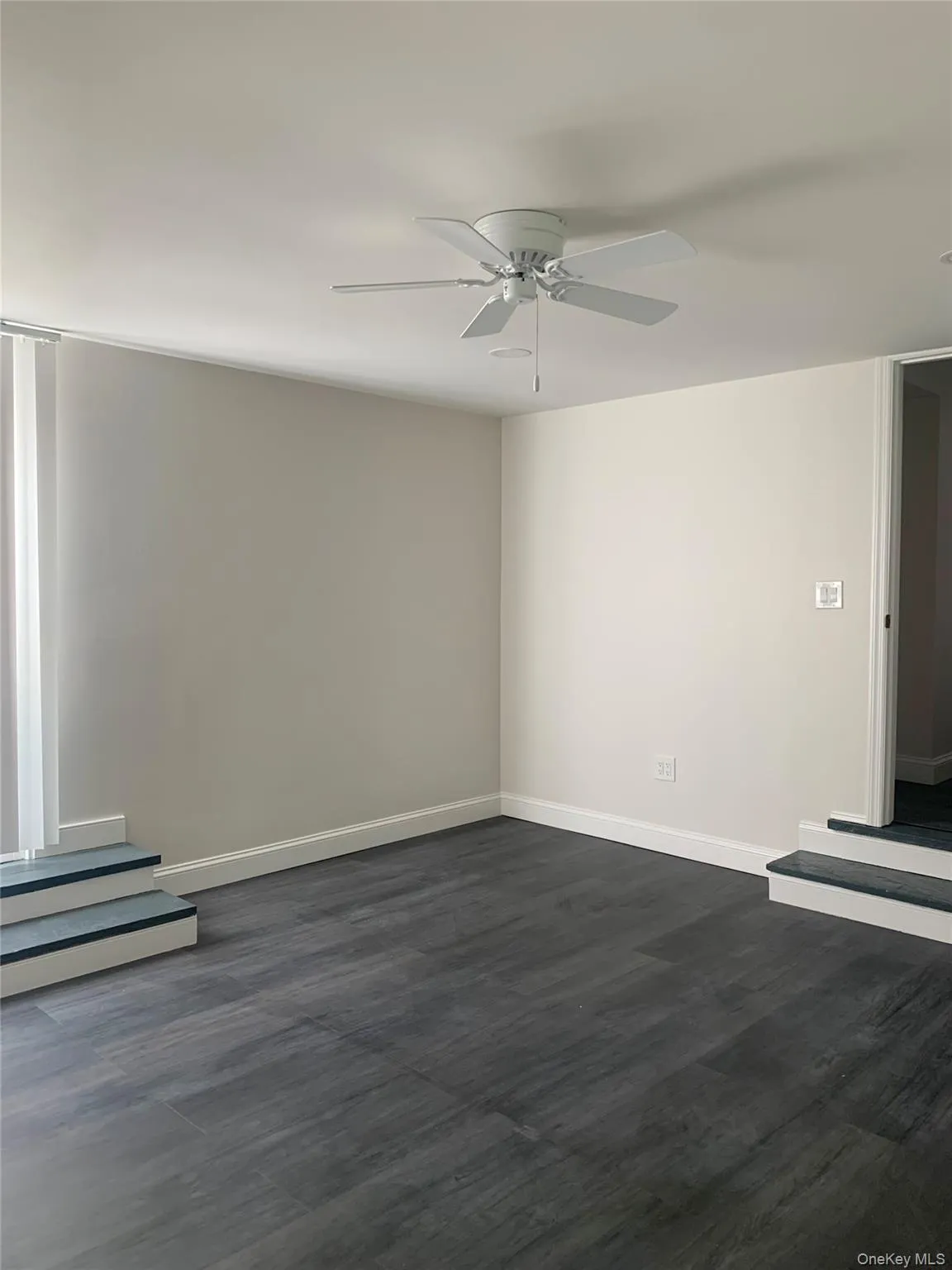 Unfurnished room featuring dark wood-style flooring and a ceiling fan Unfurnished room featuring dark wood-style flooring and a ceiling fan