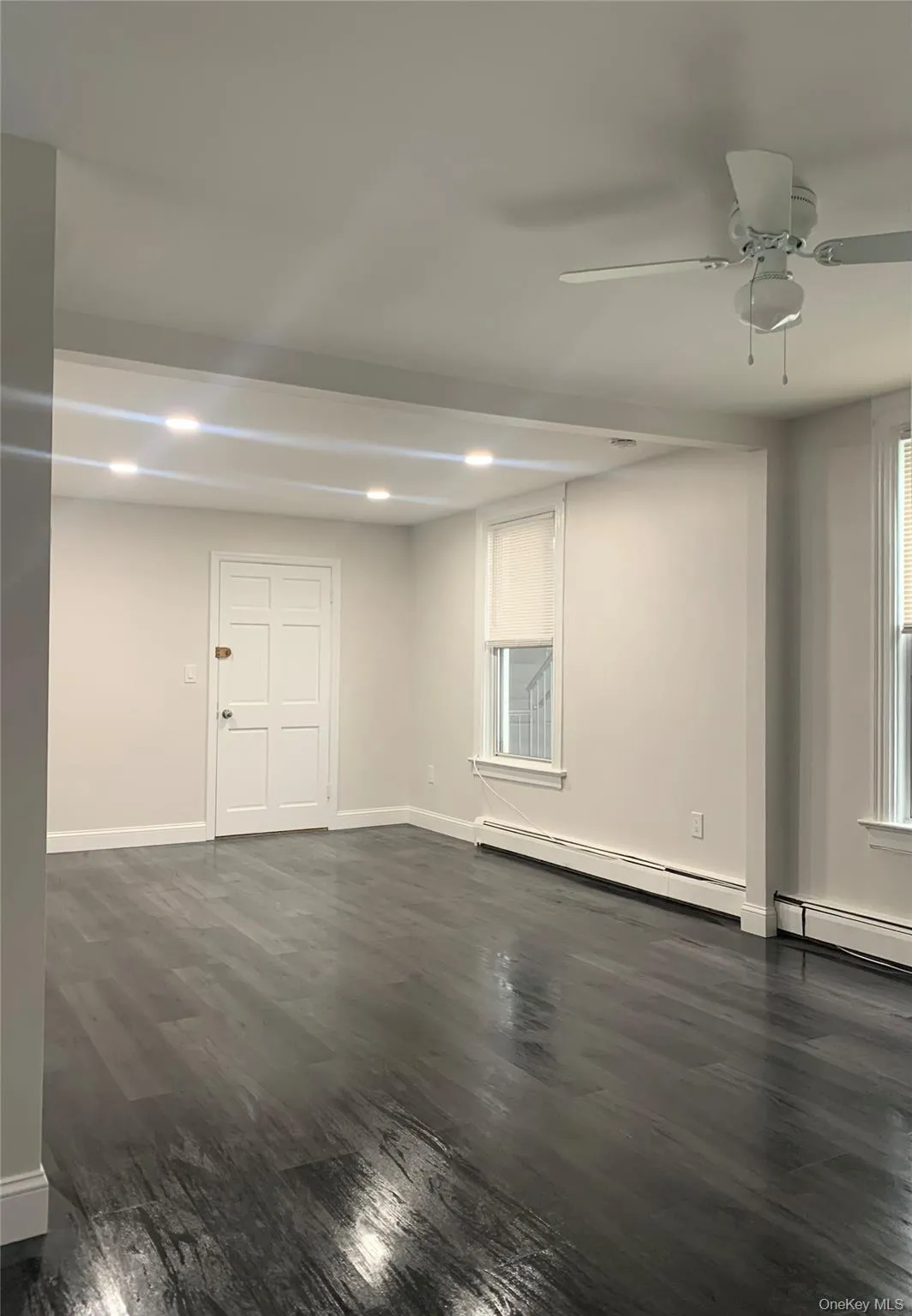 Unfurnished room with dark wood-style floors, ceiling fan, recessed lighting, and a baseboard heating unit Unfurnished room with dark wood-style floors, ceiling fan, recessed lighting, and a baseboard heating unit