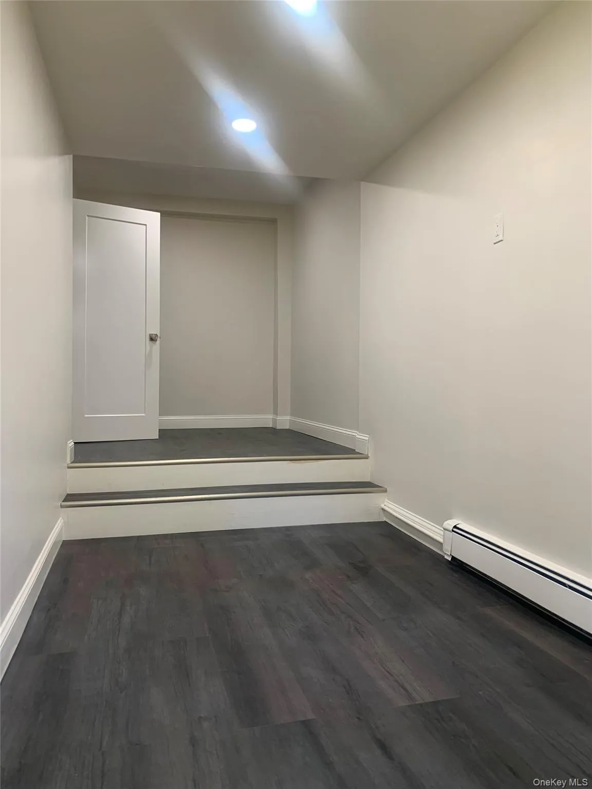 Spare room featuring baseboard heating and dark wood finished floors Spare room featuring baseboard heating and dark wood finished floors