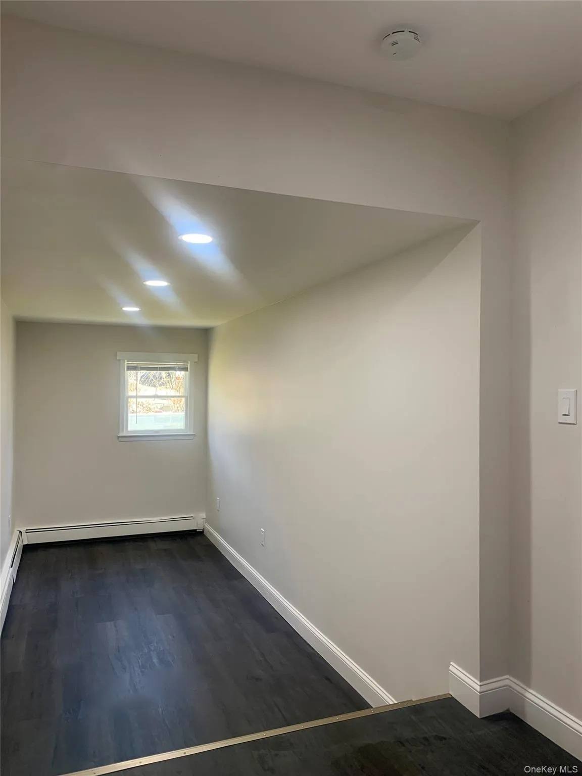 Spare room with dark wood-style flooring and baseboards Spare room with dark wood-style flooring and baseboards