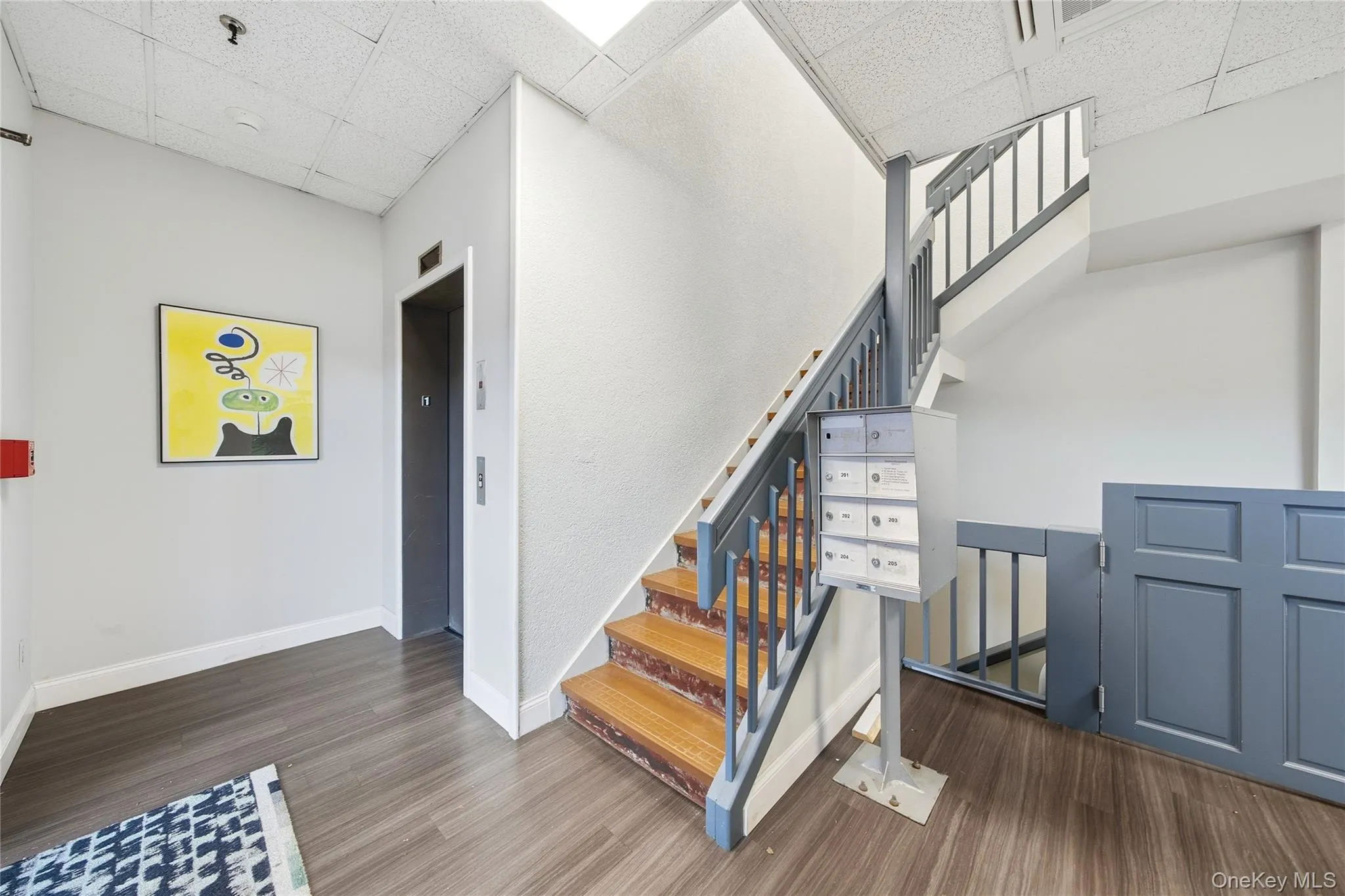 Staircase with a paneled ceiling, wood finished floors, and elevator Staircase with a paneled ceiling, wood finished floors, and elevator