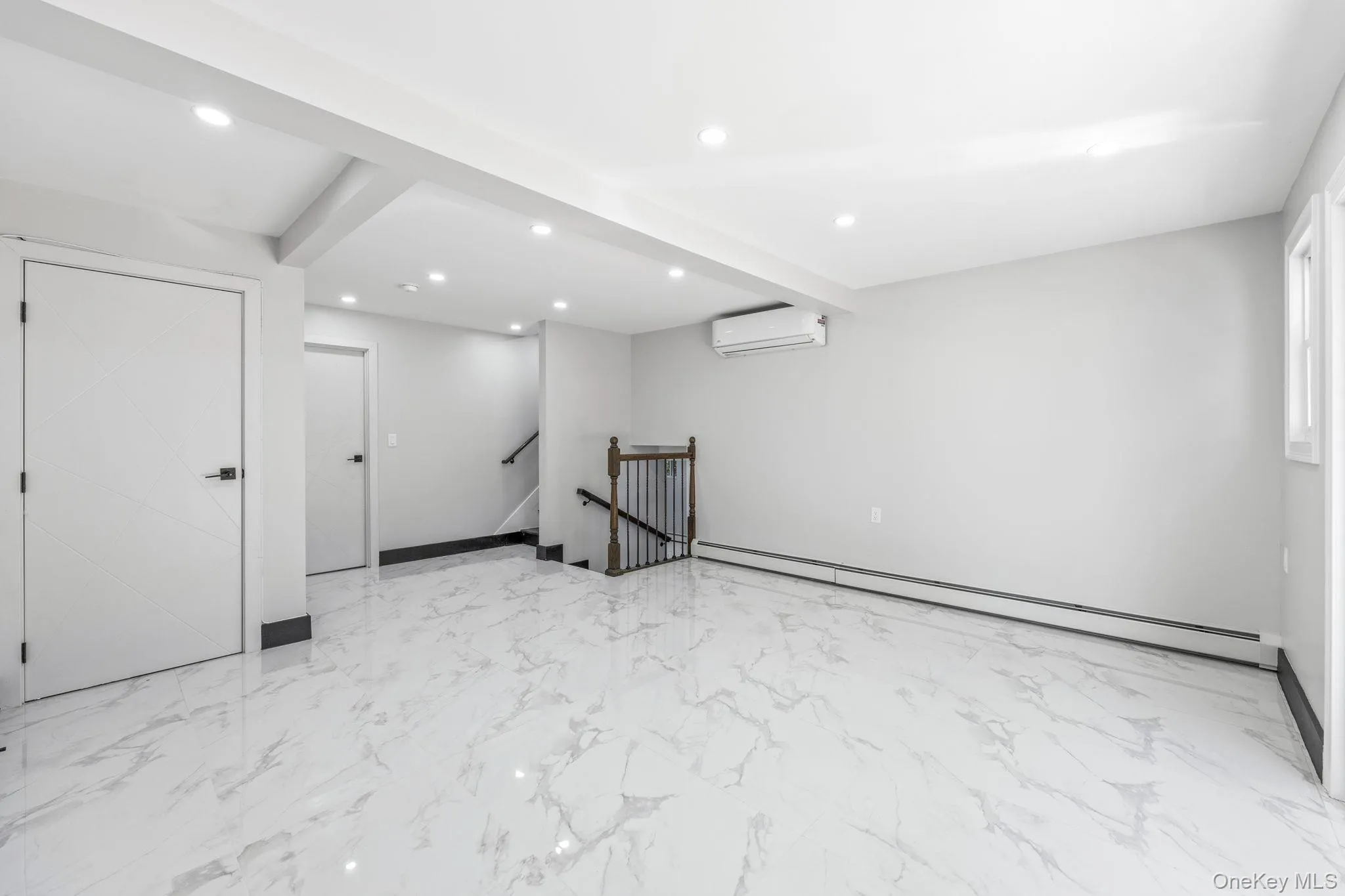 Basement featuring recessed lighting, a baseboard heating unit, and light marble finish flooring Basement featuring recessed lighting, a baseboard heating unit, and light marble finish flooring