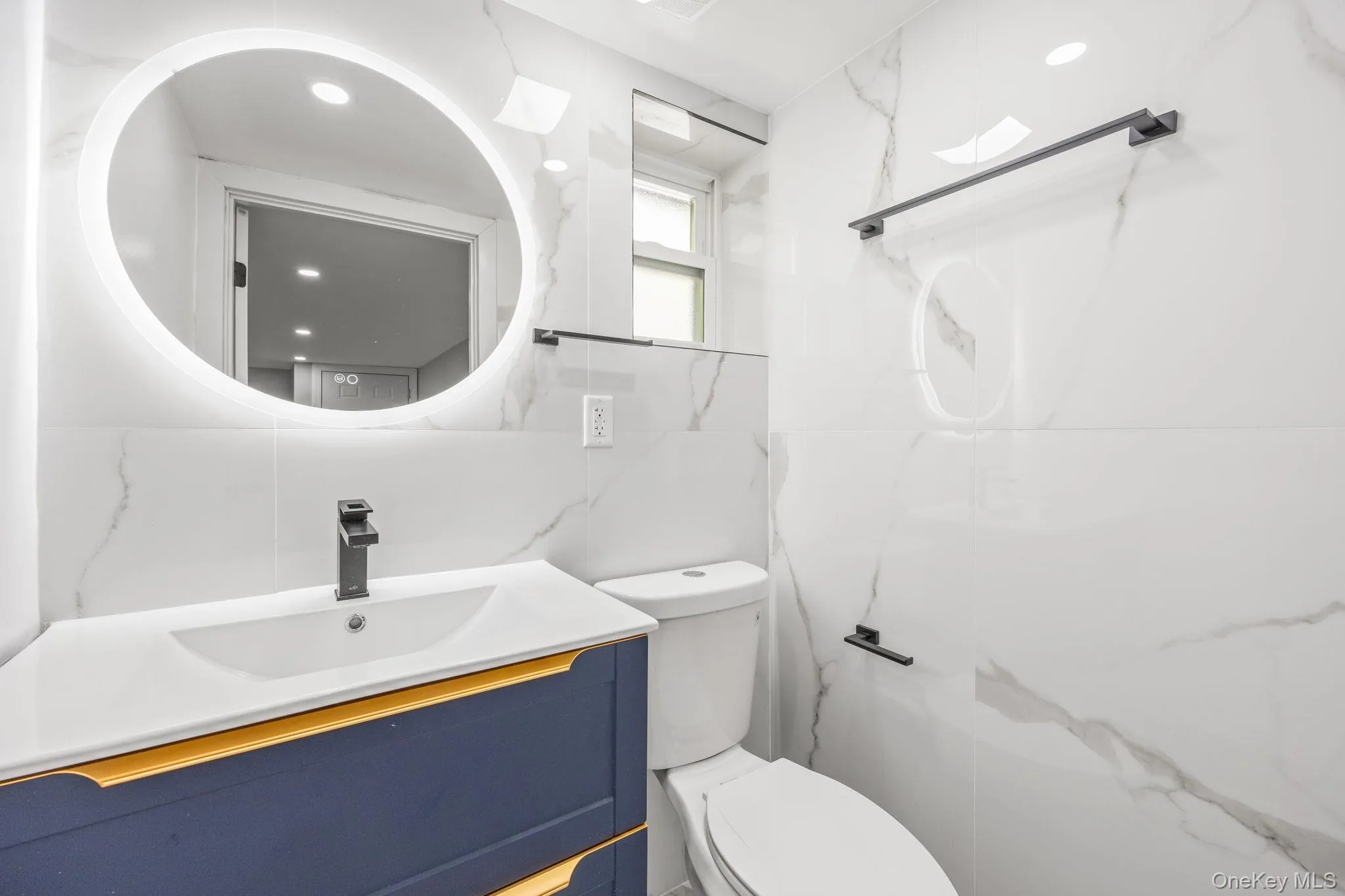 Bathroom with vanity, a marble finish shower, and tile walls Bathroom with vanity, a marble finish shower, and tile walls