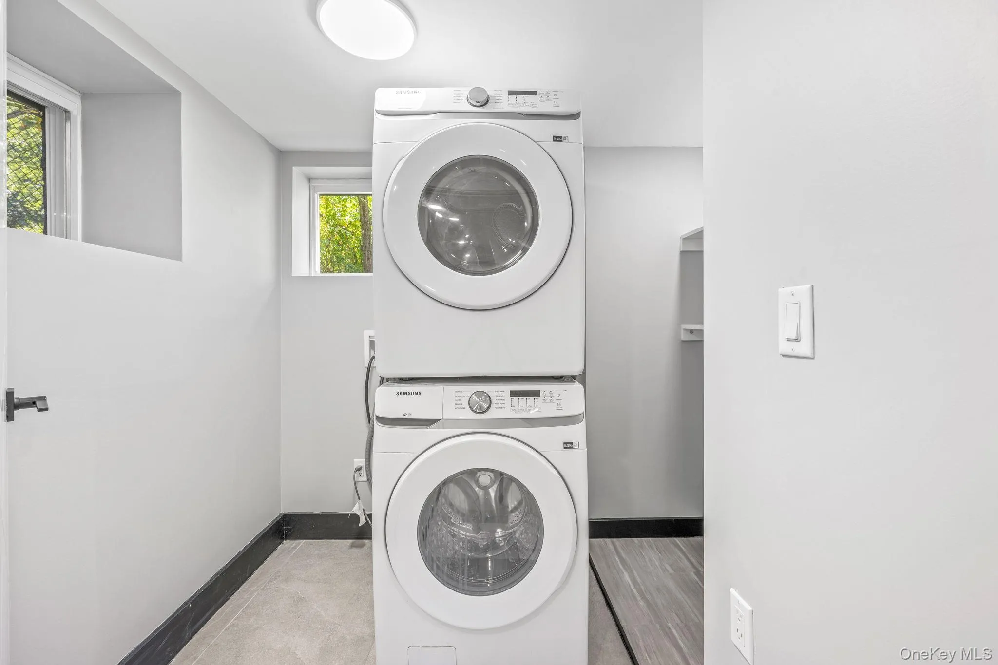 Washroom with stacked washer / drying machine and baseboards Washroom with stacked washer / drying machine and baseboards