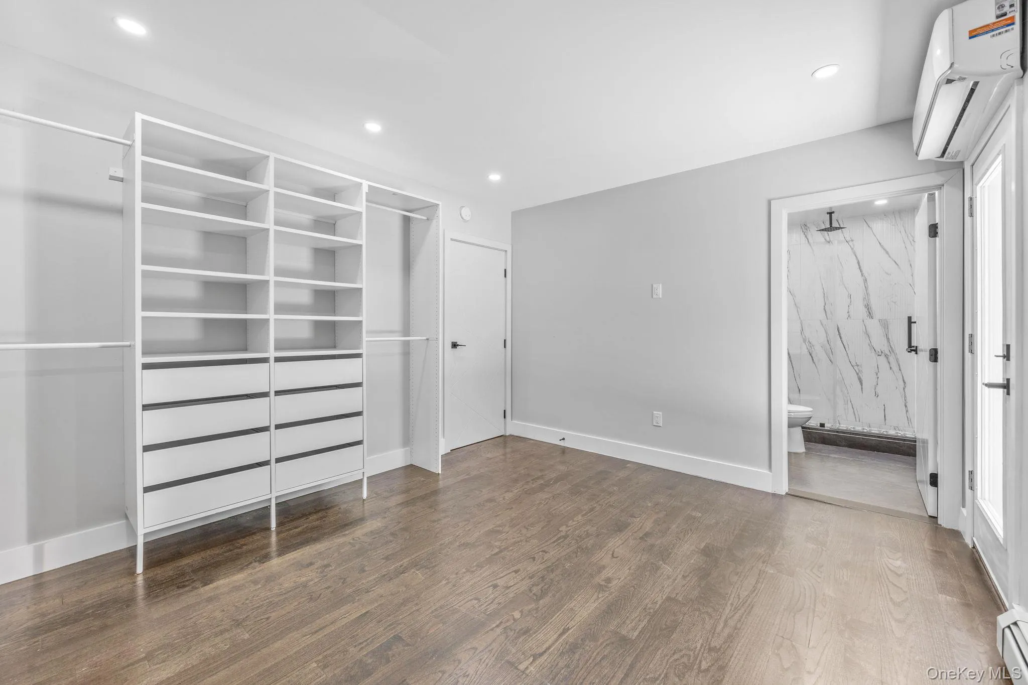 Unfurnished bedroom featuring an AC wall unit, dark wood-type flooring, a closet, a baseboard heating unit, and recessed lighting Unfurnished bedroom featuring an AC wall unit, dark wood-type flooring, a closet, a baseboard heating unit, and recessed lighting