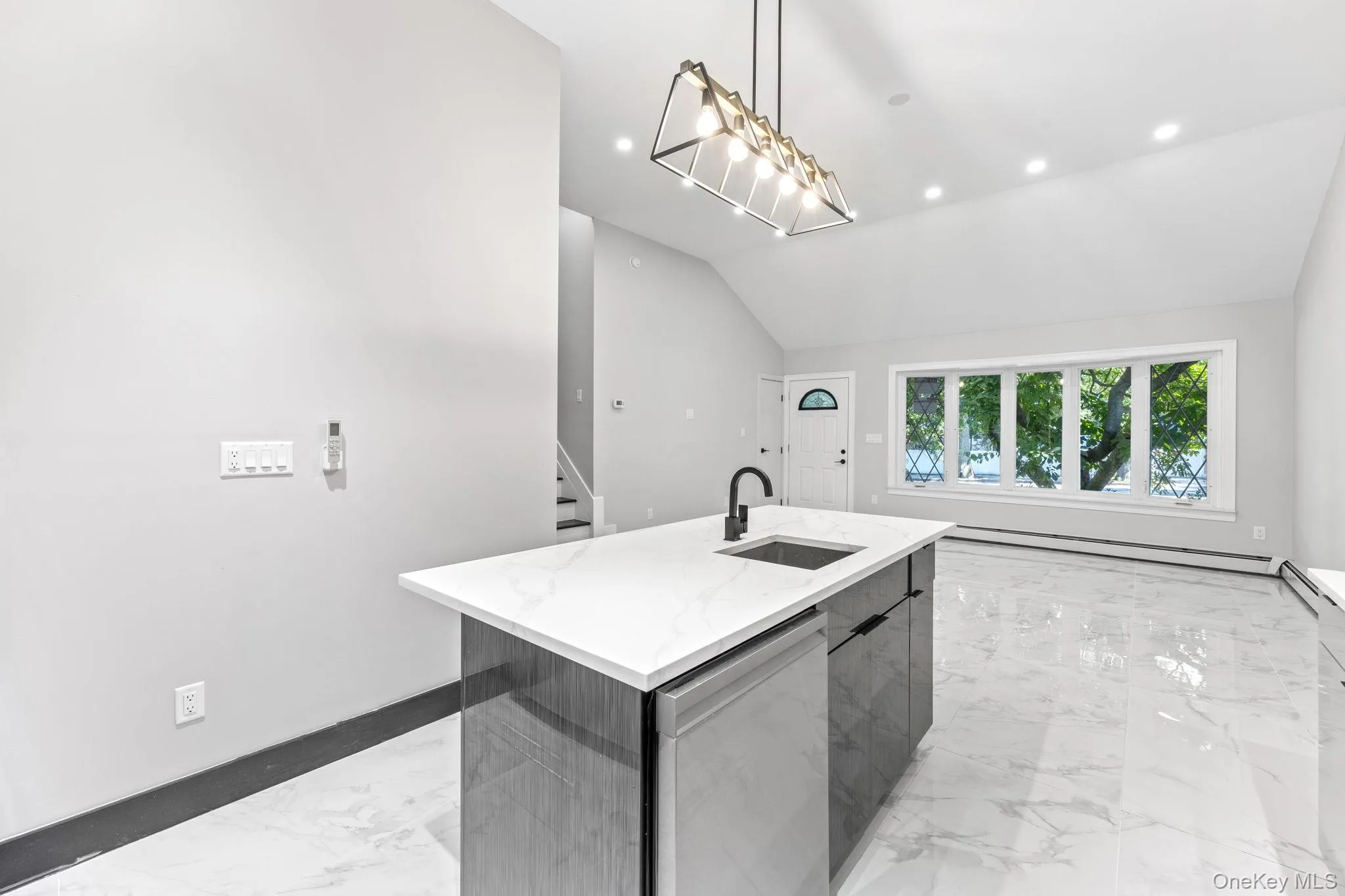 Kitchen with light marble finish flooring, modern cabinets, stainless steel dishwasher, a kitchen island with sink, and recessed lighting Kitchen with light marble finish flooring, modern cabinets, stainless steel dishwasher, a kitchen island with sink, and recessed lighting