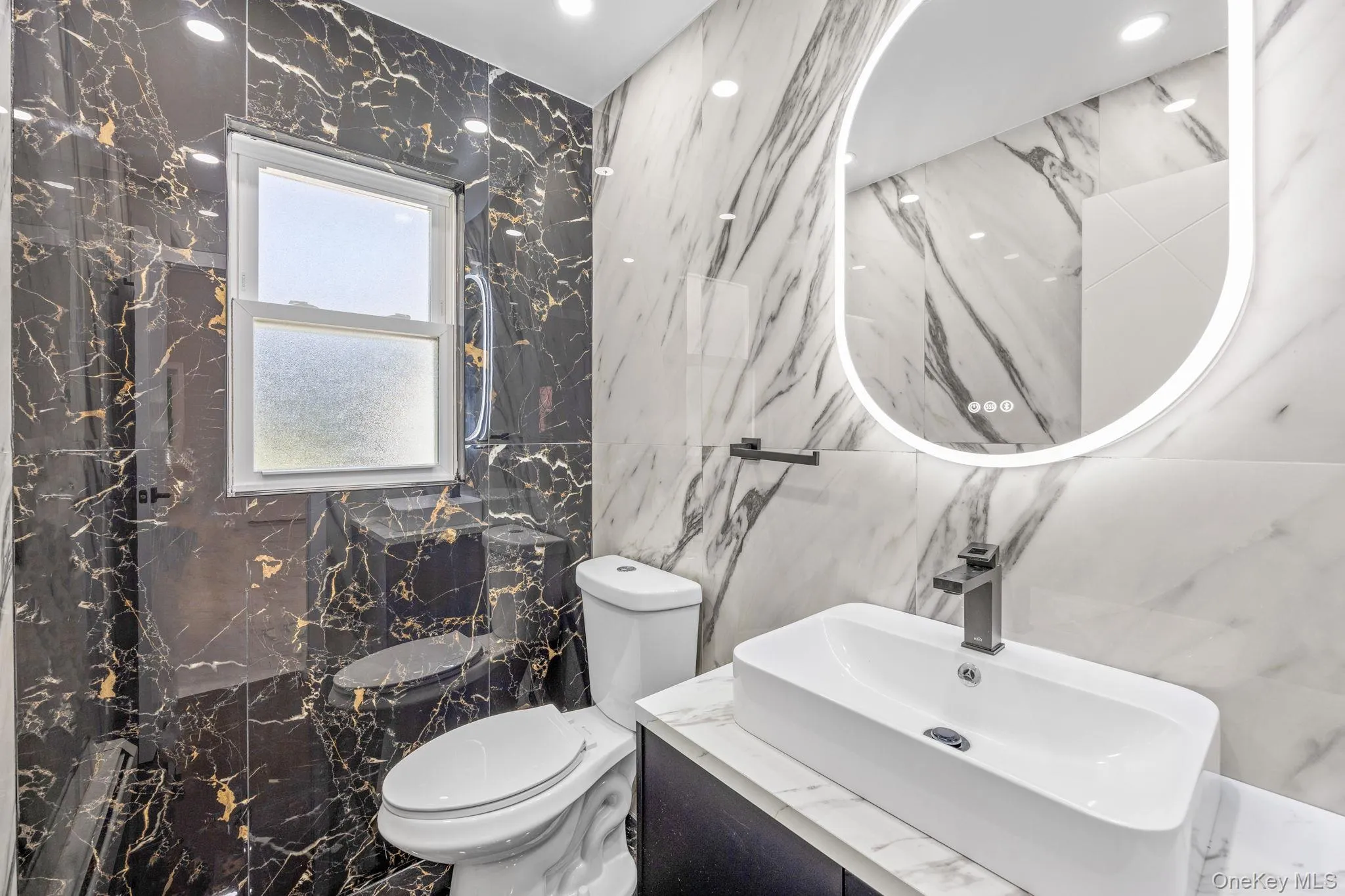 Bathroom featuring stone wall, tile walls, vanity, marble tiled flooring, and a marble finish shower Bathroom featuring stone wall, tile walls, vanity, marble tiled flooring, and a marble finish shower