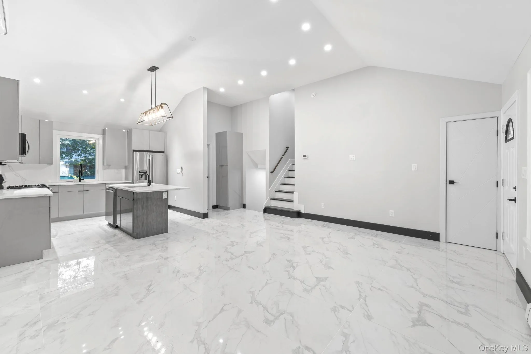 Kitchen with a center island, light marble finish floors, a breakfast bar, gray cabinetry, and open floor plan Kitchen with a center island, light marble finish floors, a breakfast bar, gray cabinetry, and open floor plan