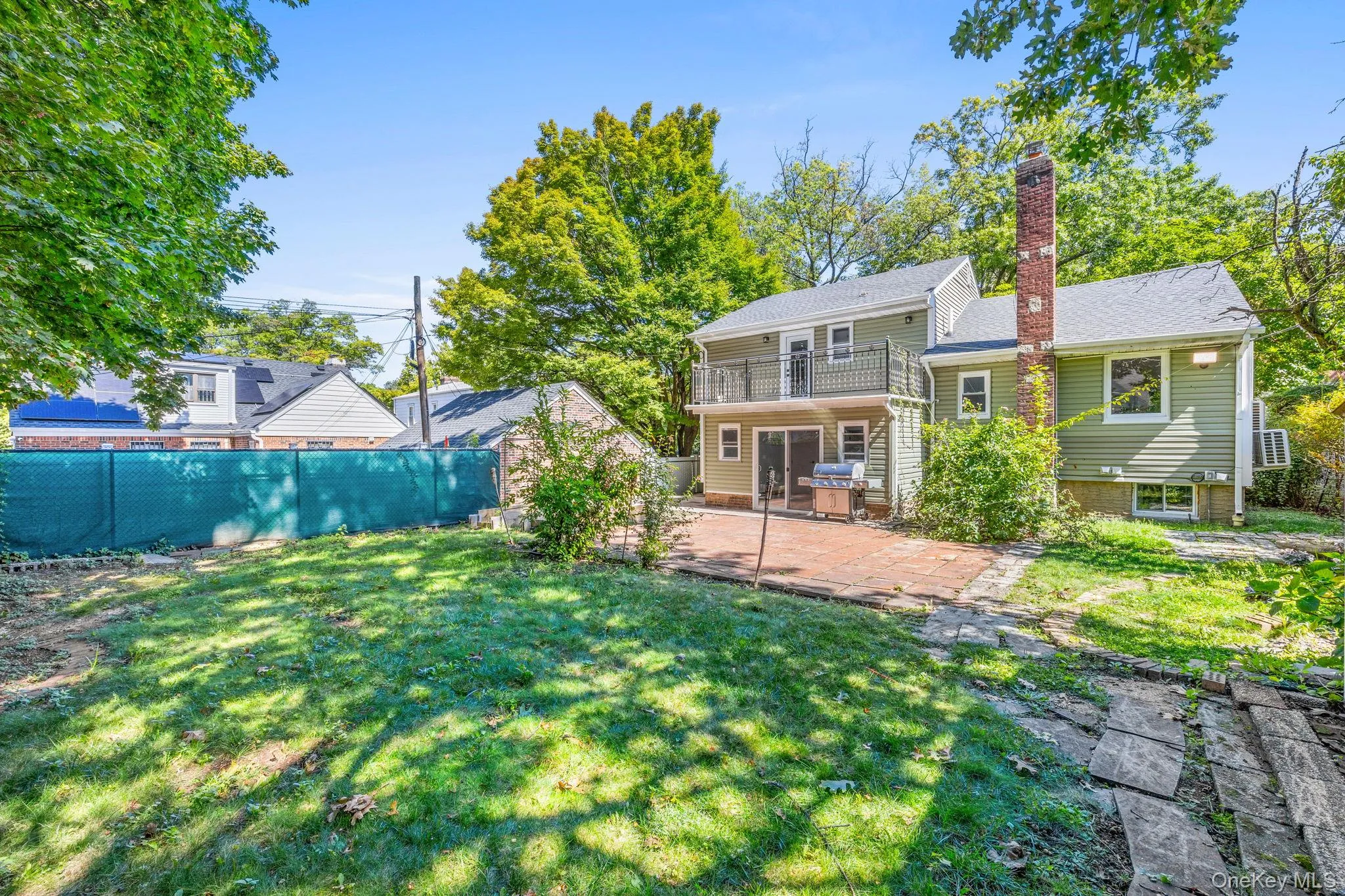 Back of property with a patio, a balcony, a chimney, and a fenced backyard Back of property with a patio, a balcony, a chimney, and a fenced backyard