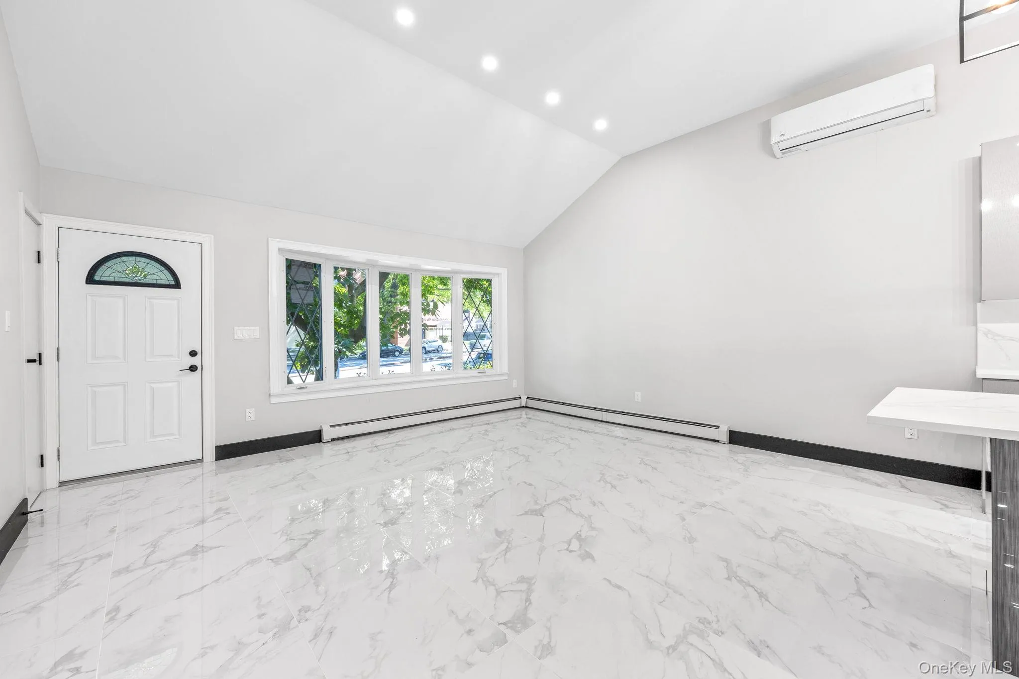Foyer entrance featuring light marble finish floors, recessed lighting, lofted ceiling, an AC wall unit, and a baseboard heating unit Foyer entrance featuring light marble finish floors, recessed lighting, lofted ceiling, an AC wall unit, and a baseboard heating unit