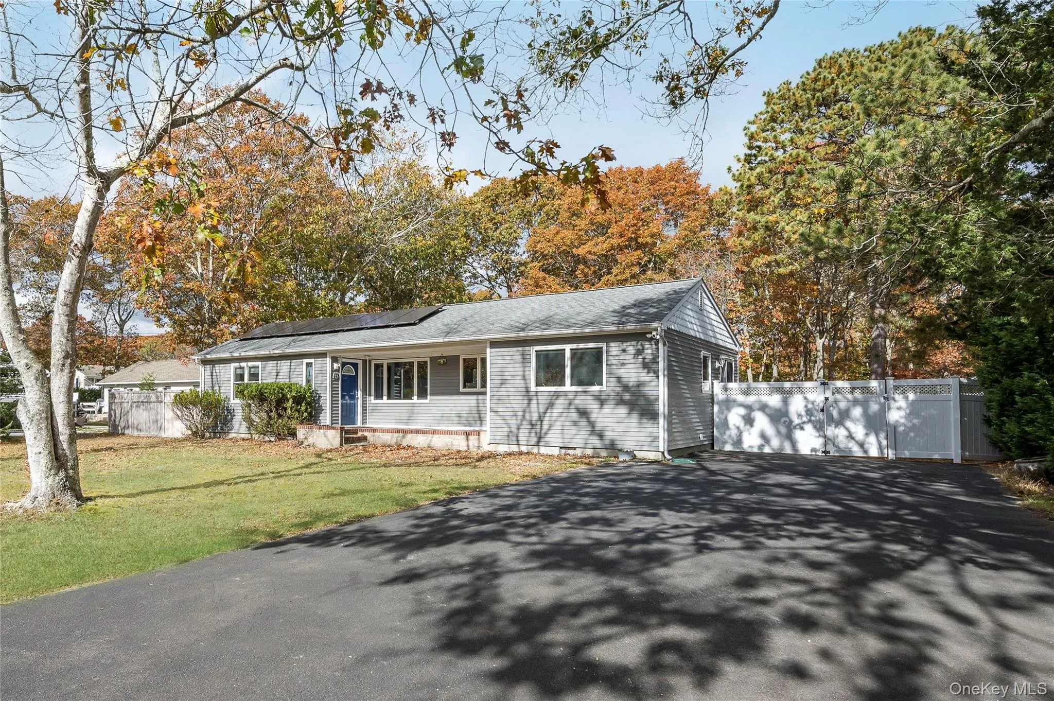 Ranch-style home with asphalt driveway, solar panels, and a porch
