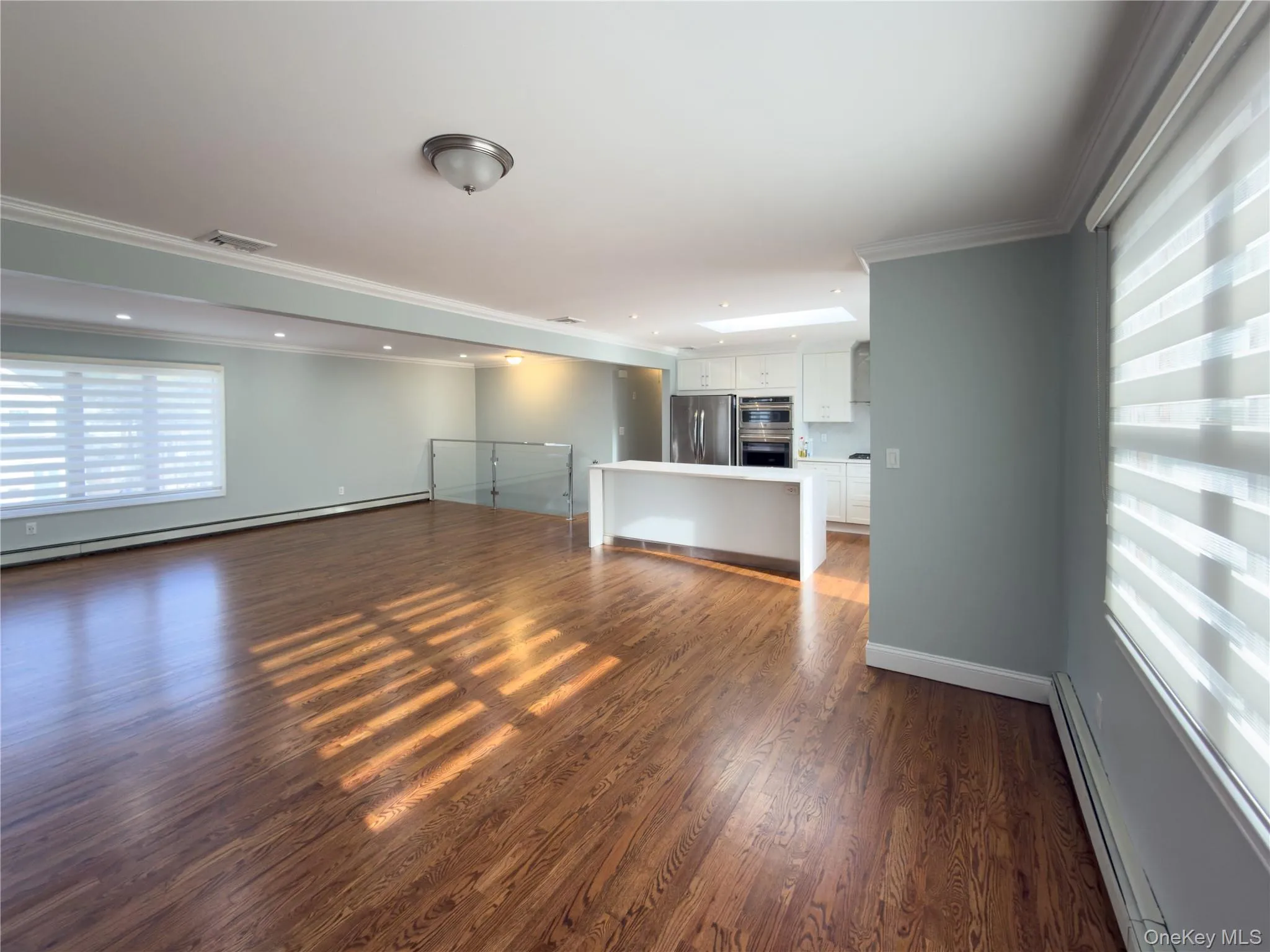 Unfurnished living room with a baseboard heating unit, crown molding, dark wood-style flooring, and a baseboard radiator Unfurnished living room with a baseboard heating unit, crown molding, dark wood-style flooring, and a baseboard radiator