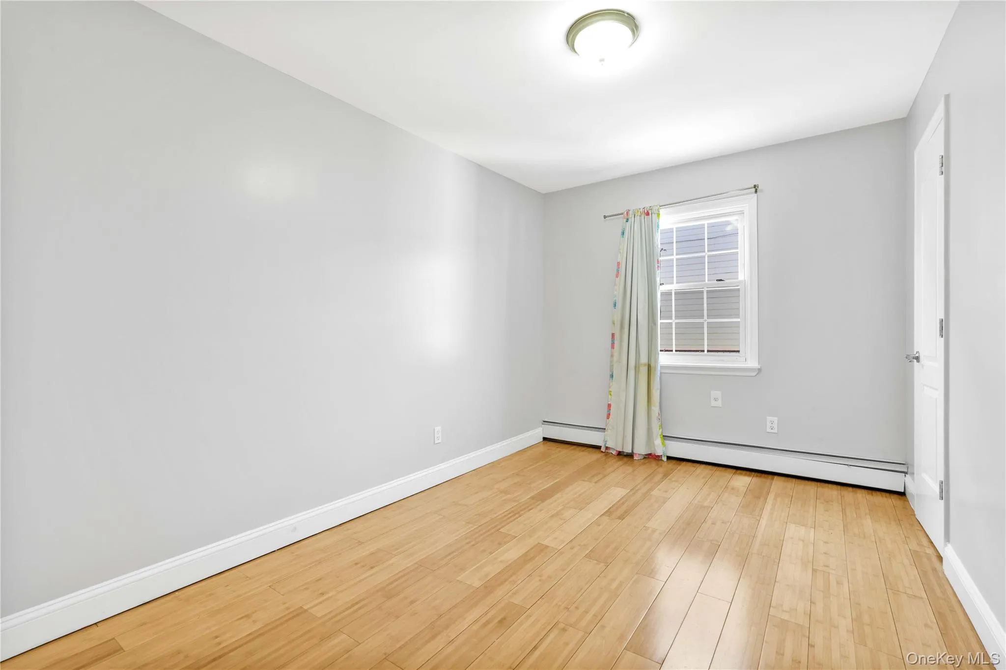 Spare room with baseboards, wood finished floors, and a baseboard heating unit Spare room with baseboards, wood finished floors, and a baseboard heating unit