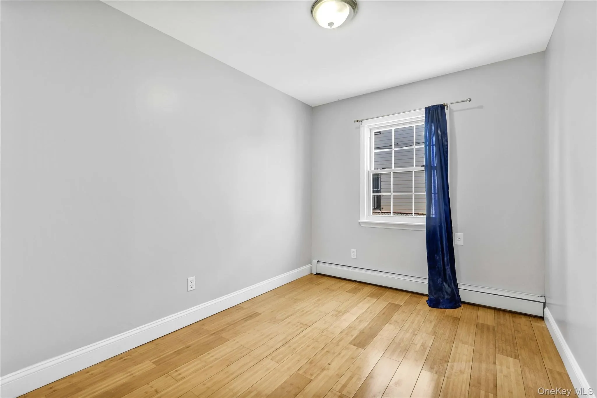 Unfurnished room featuring baseboards, a baseboard heating unit, and hardwood / wood-style flooring Unfurnished room featuring baseboards, a baseboard heating unit, and hardwood / wood-style flooring