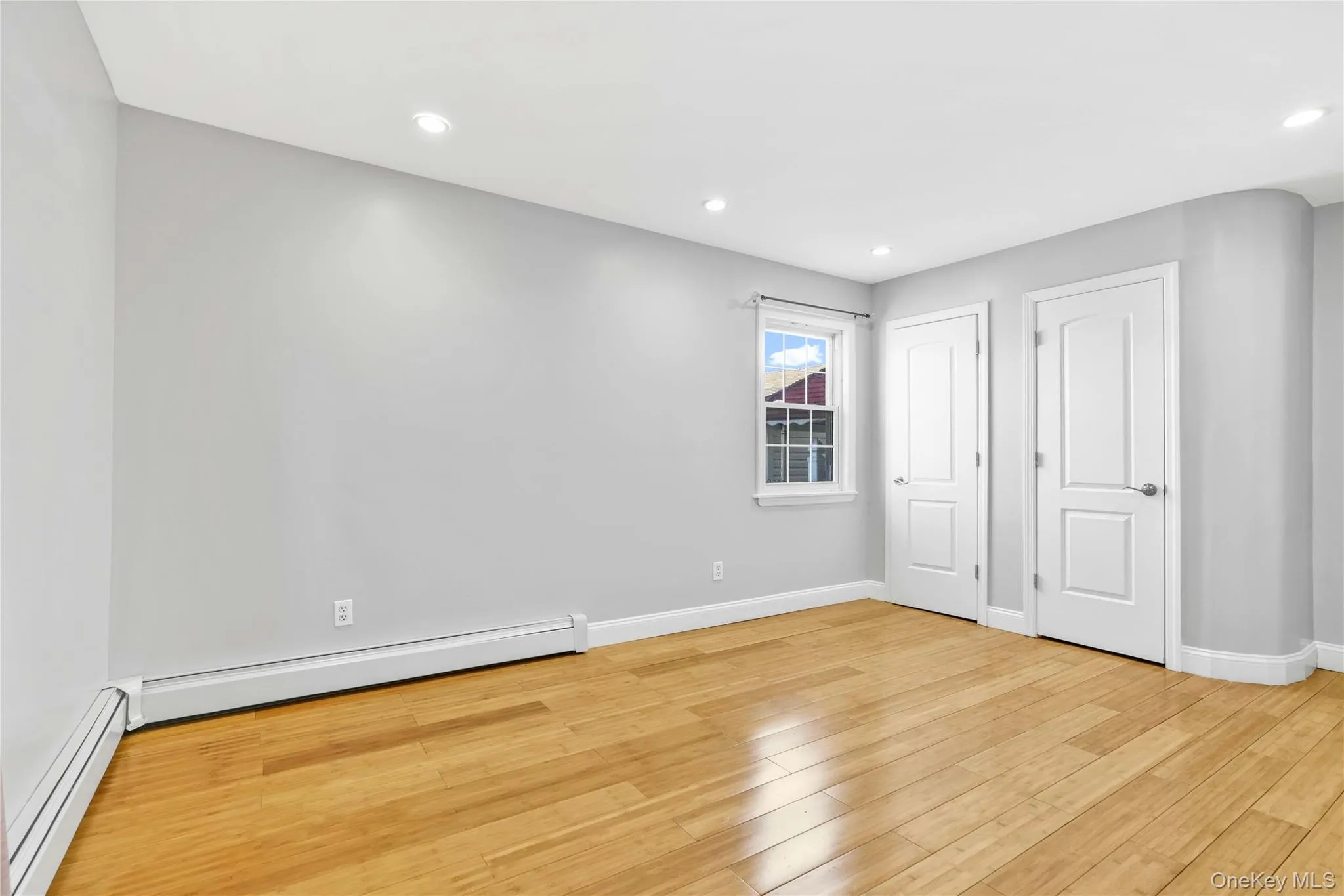 Unfurnished bedroom featuring light wood-style flooring, baseboards, and baseboard heating Unfurnished bedroom featuring light wood-style flooring, baseboards, and baseboard heating