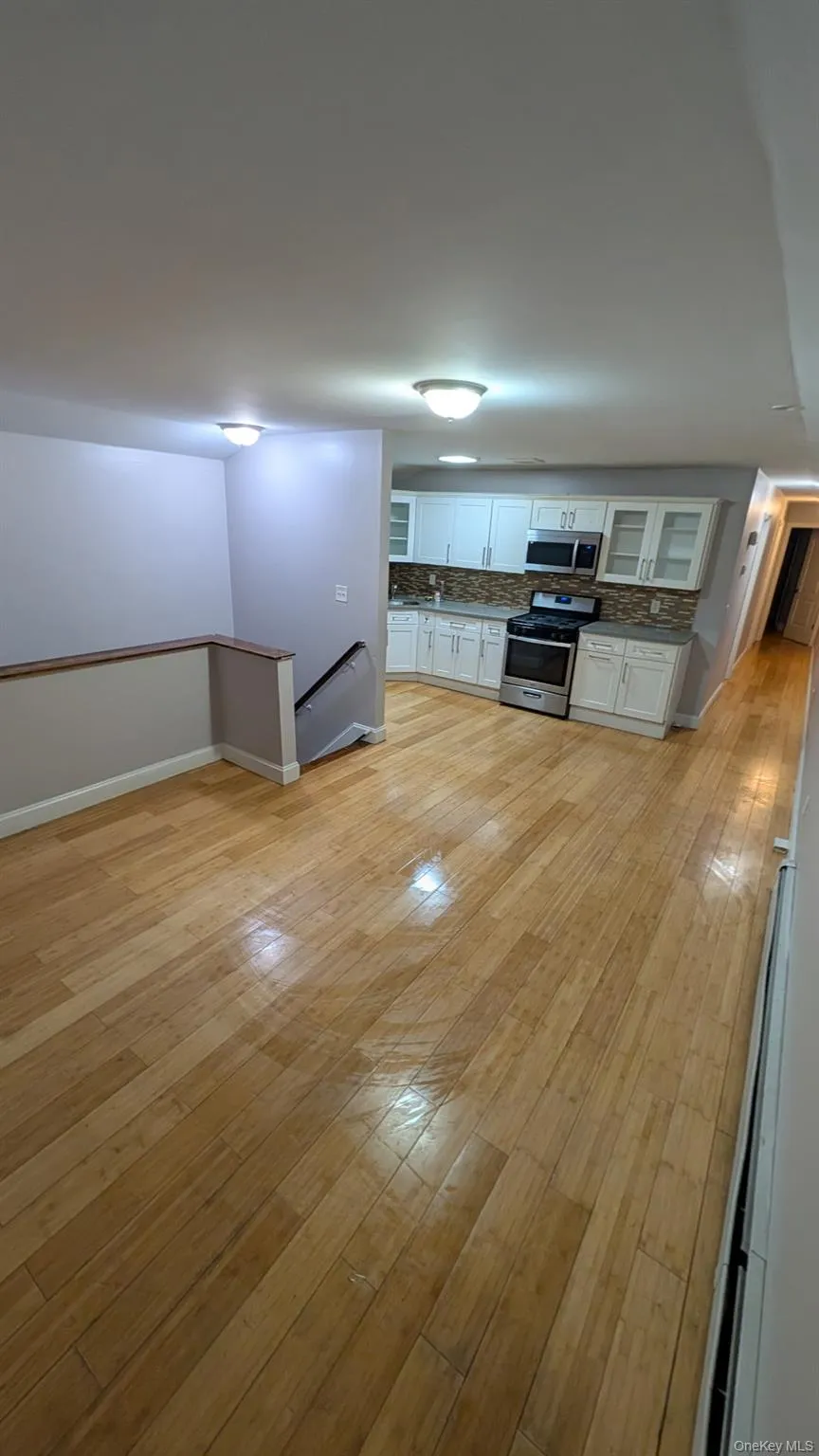 Kitchen with white cabinets, backsplash, light wood finished floors, appliances with stainless steel finishes, and glass insert cabinets Kitchen with white cabinets, backsplash, light wood finished floors, appliances with stainless steel finishes, and glass insert cabinets