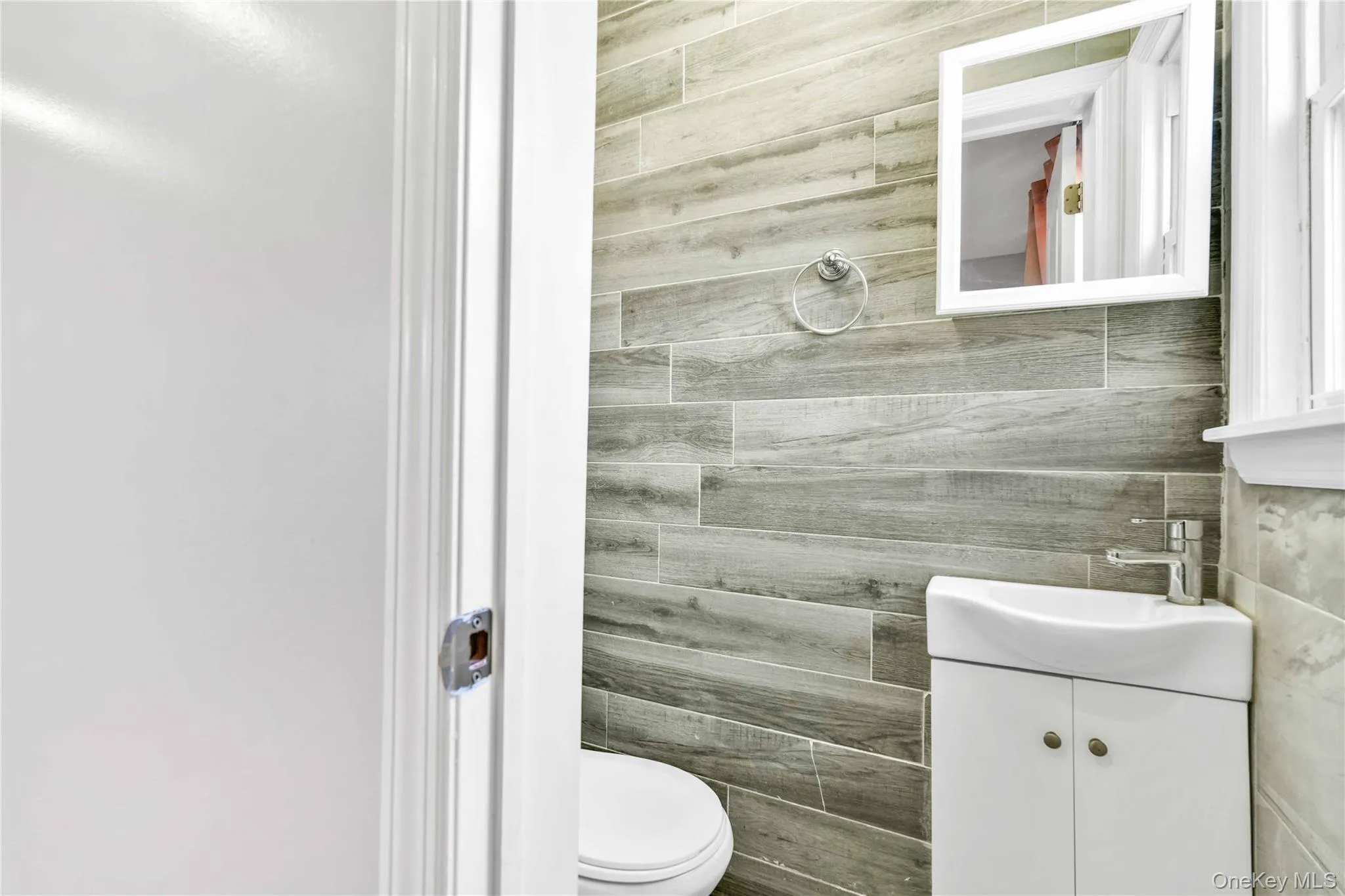 Half bath featuring toilet, vanity, and tile walls Half bath featuring toilet, vanity, and tile walls