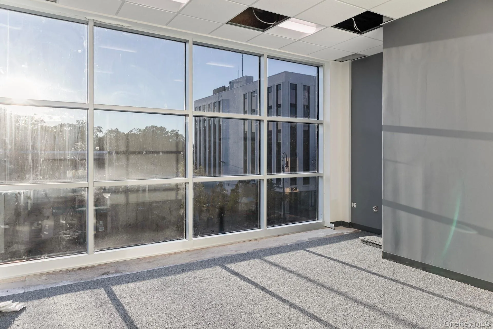 Empty room with floor to ceiling windows and a paneled ceiling Empty room with floor to ceiling windows and a paneled ceiling