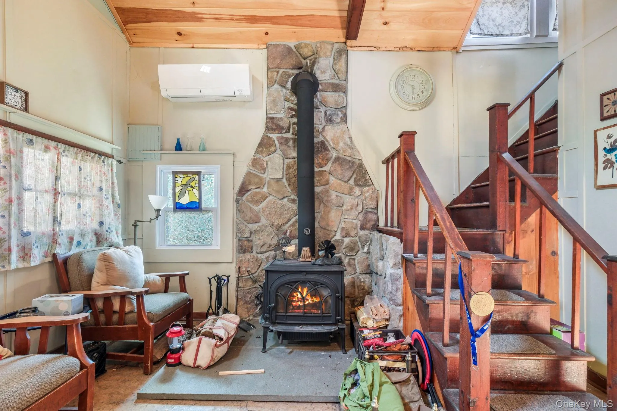 Living room featuring a wood stove, wood finished floors, healthy amount of natural light, ceiling fan, and a high wooden beamed ceiling Living room featuring a wood stove, wood finished floors, healthy amount of natural light, ceiling fan, and a high wooden beamed ceiling
