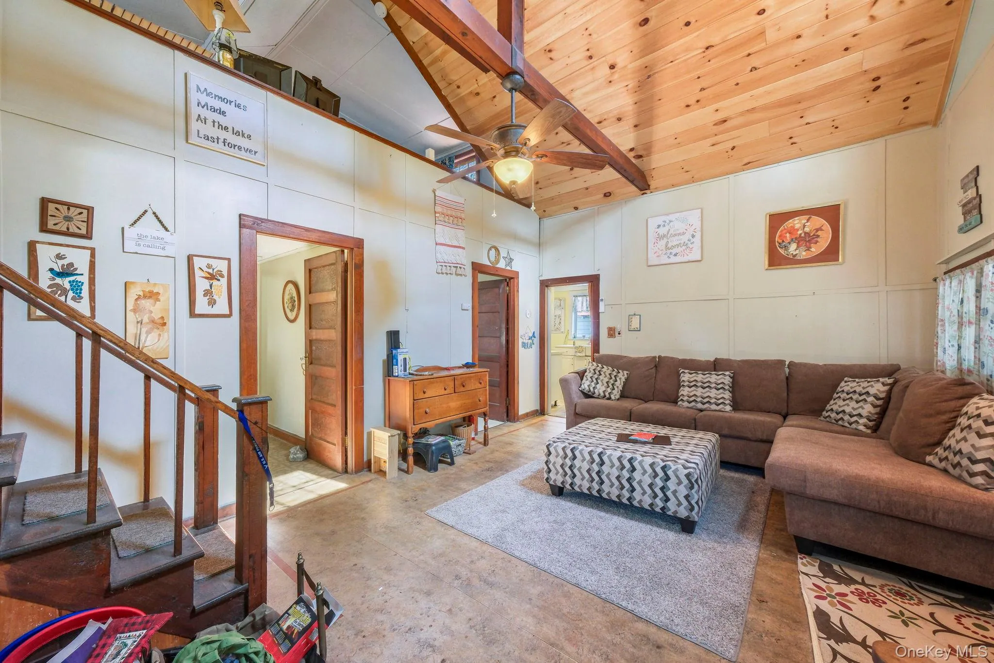 Living room featuring a ceiling fan, a decorative wall, concrete flooring, and a vaulted wood ceiling Living room featuring a ceiling fan, a decorative wall, concrete flooring, and a vaulted wood ceiling