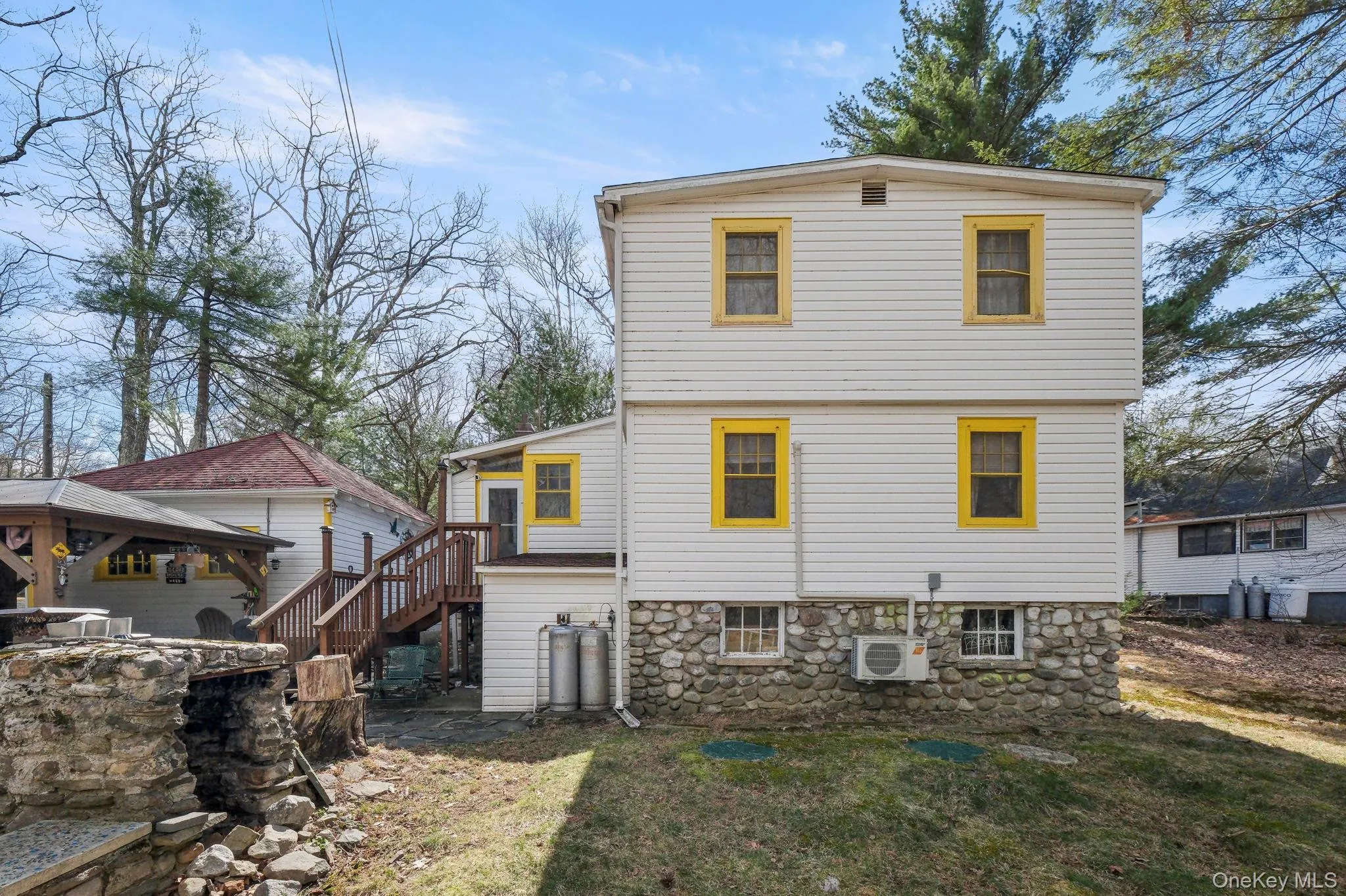 Rear view of property featuring a patio, a yard, a wooden deck, and stone siding Rear view of property featuring a patio, a yard, a wooden deck, and stone siding