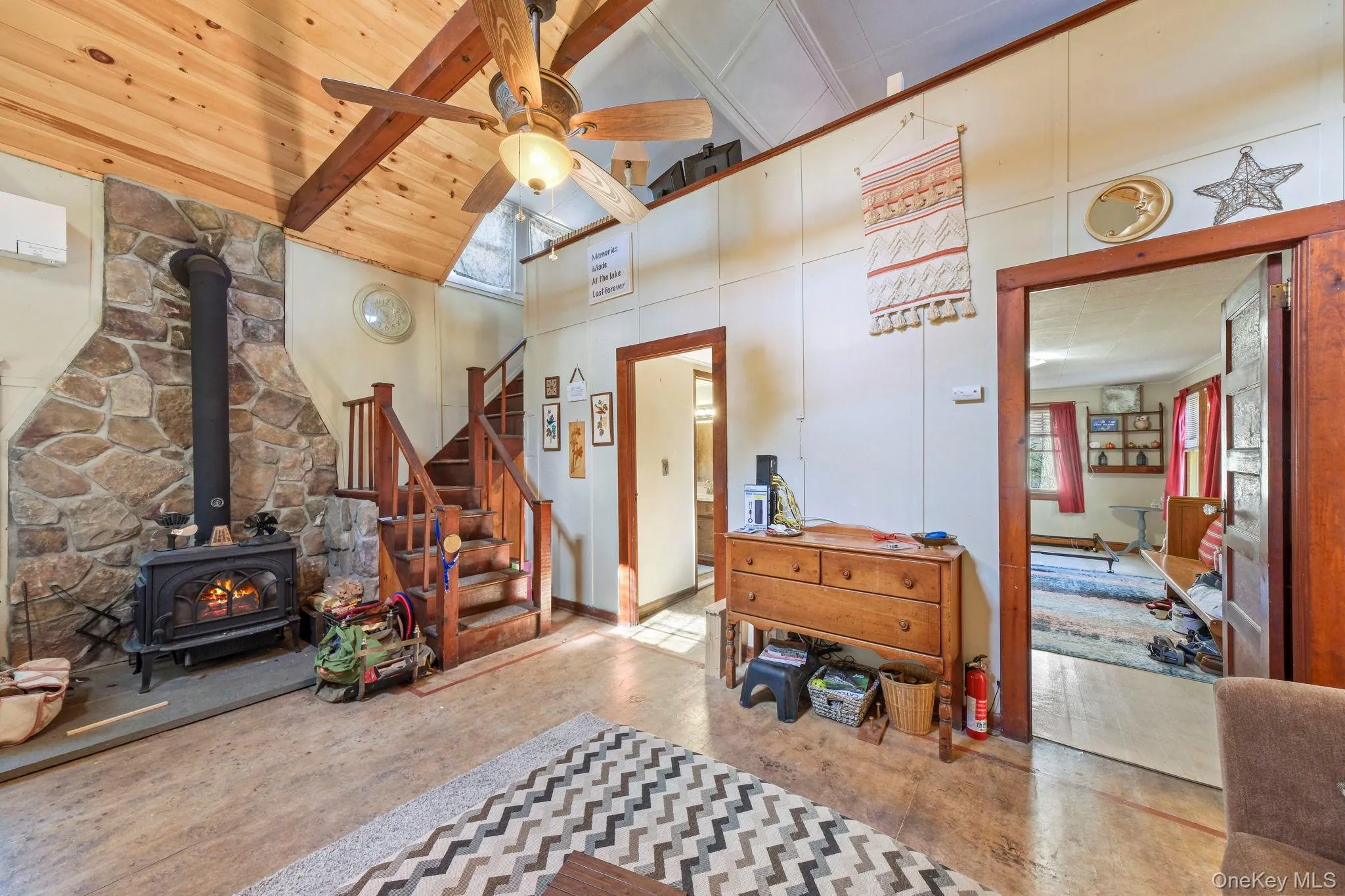 Entrance foyer with a wood stove, a ceiling fan, and vaulted ceiling Entrance foyer with a wood stove, a ceiling fan, and vaulted ceiling
