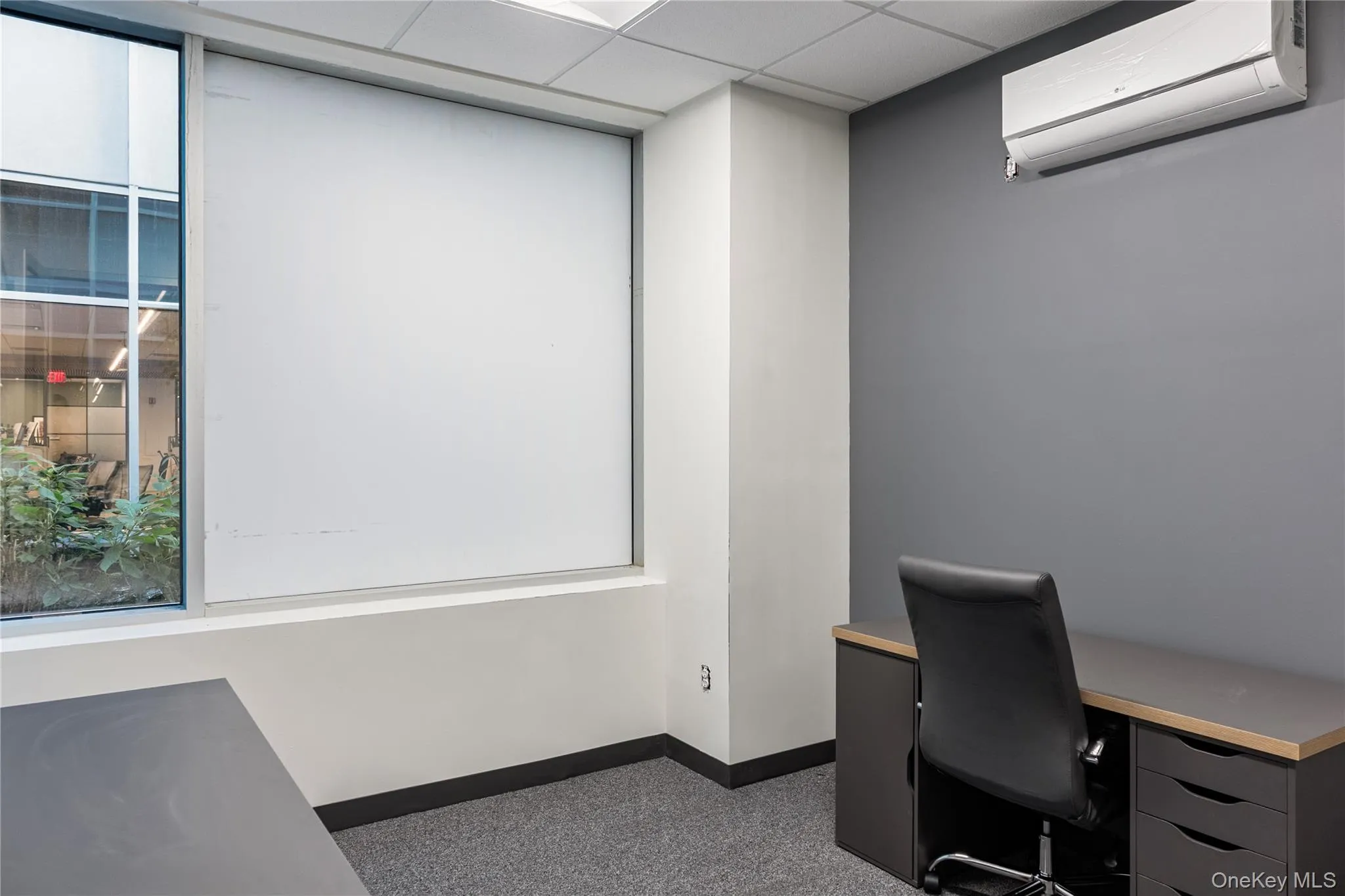 Unfurnished office with a wall mounted air conditioner and a paneled ceiling Unfurnished office with a wall mounted air conditioner and a paneled ceiling