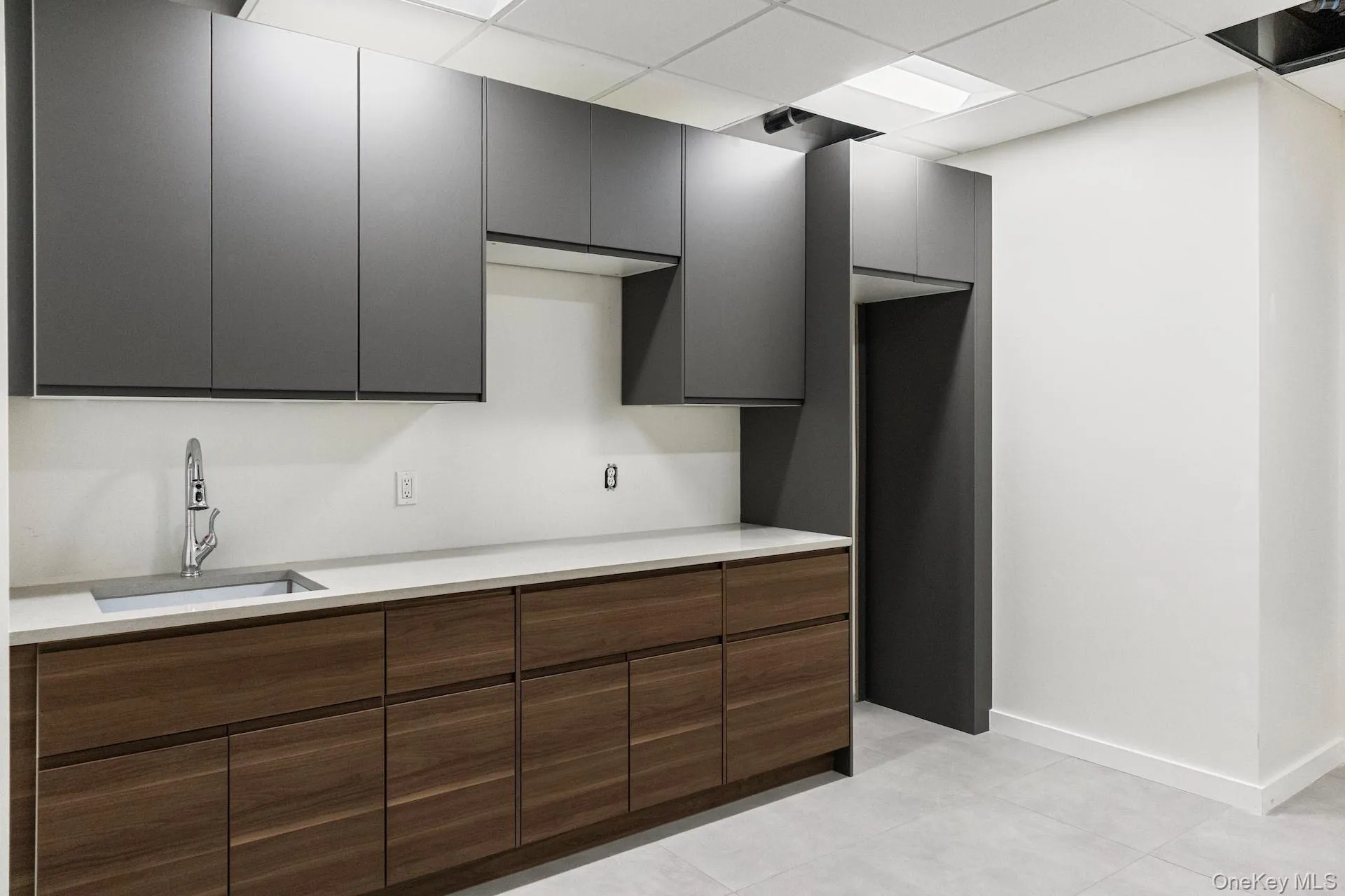 Kitchen featuring a drop ceiling, modern cabinets, and light tile patterned flooring Kitchen featuring a drop ceiling, modern cabinets, and light tile patterned flooring