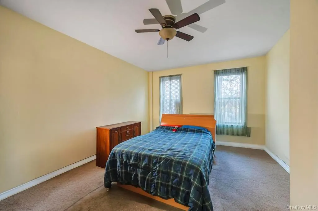 Carpeted bedroom featuring a ceiling fan and space on the opposite for an office home setup Carpeted bedroom featuring a ceiling fan and space on the opposite for an office home setup